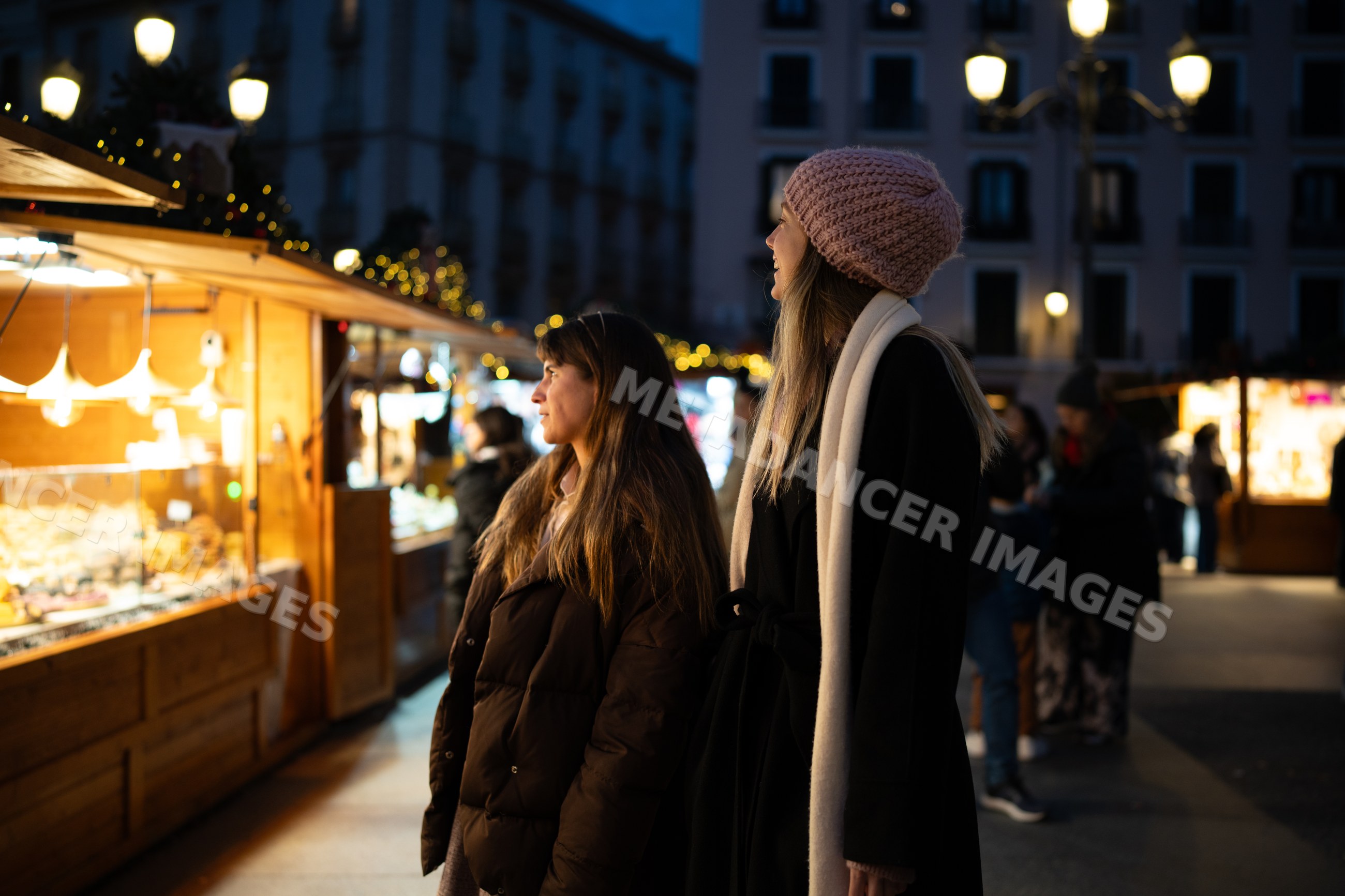 White women browsing christmas market stalls at night in Madrid, Spain