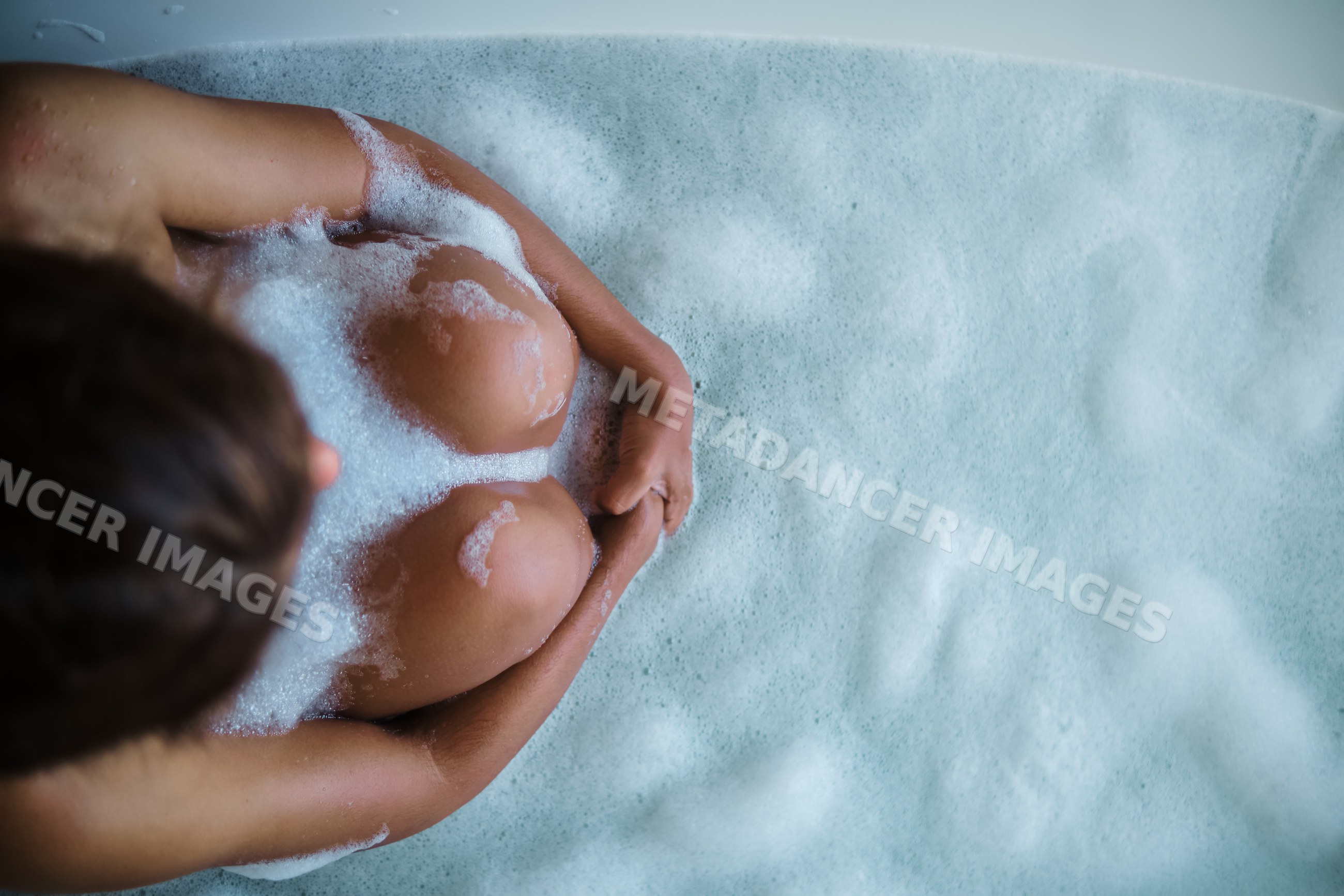 A white person enjoys a relaxing bubble bath in a bathtub