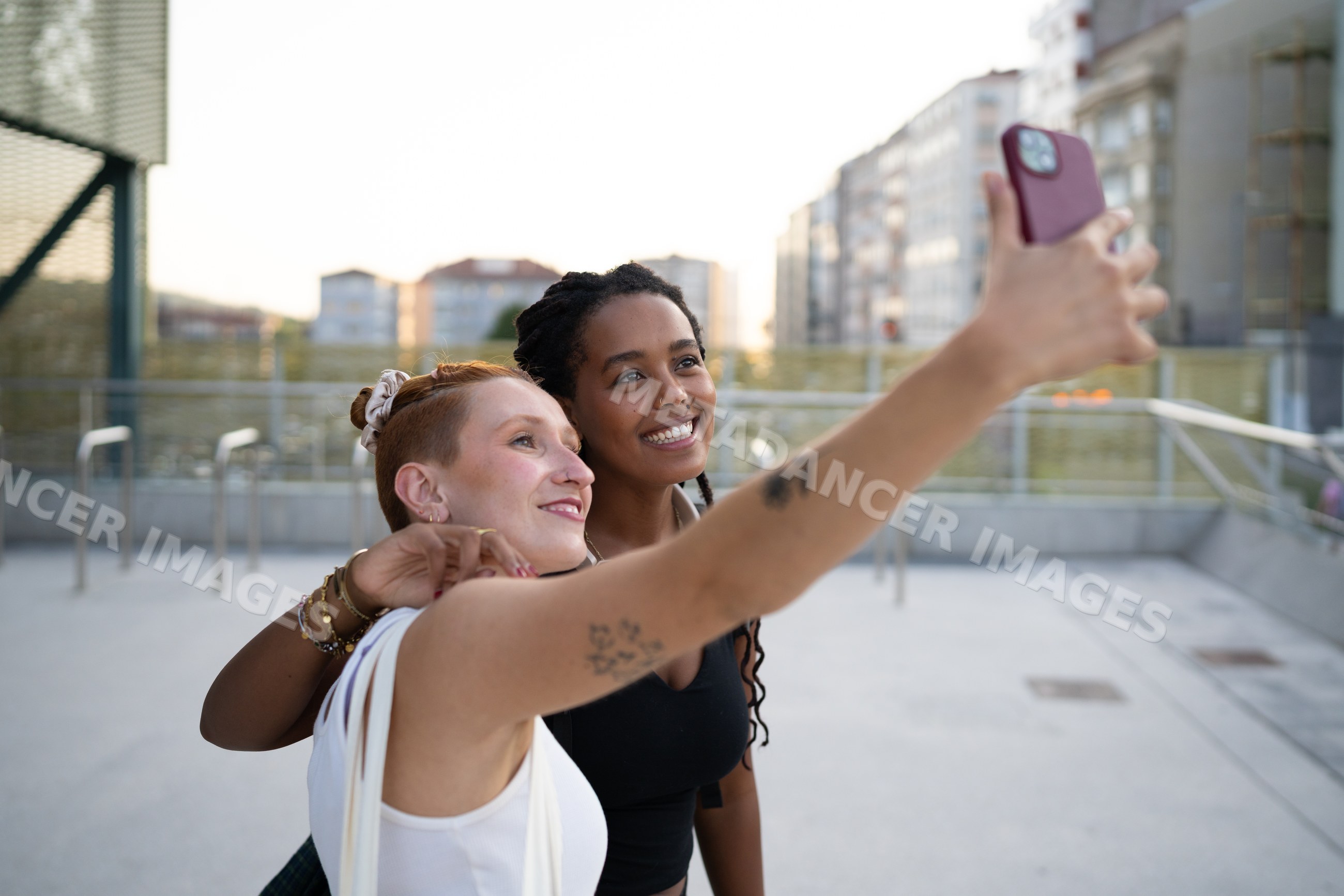 Two white and African American women taking a selfie outdoors