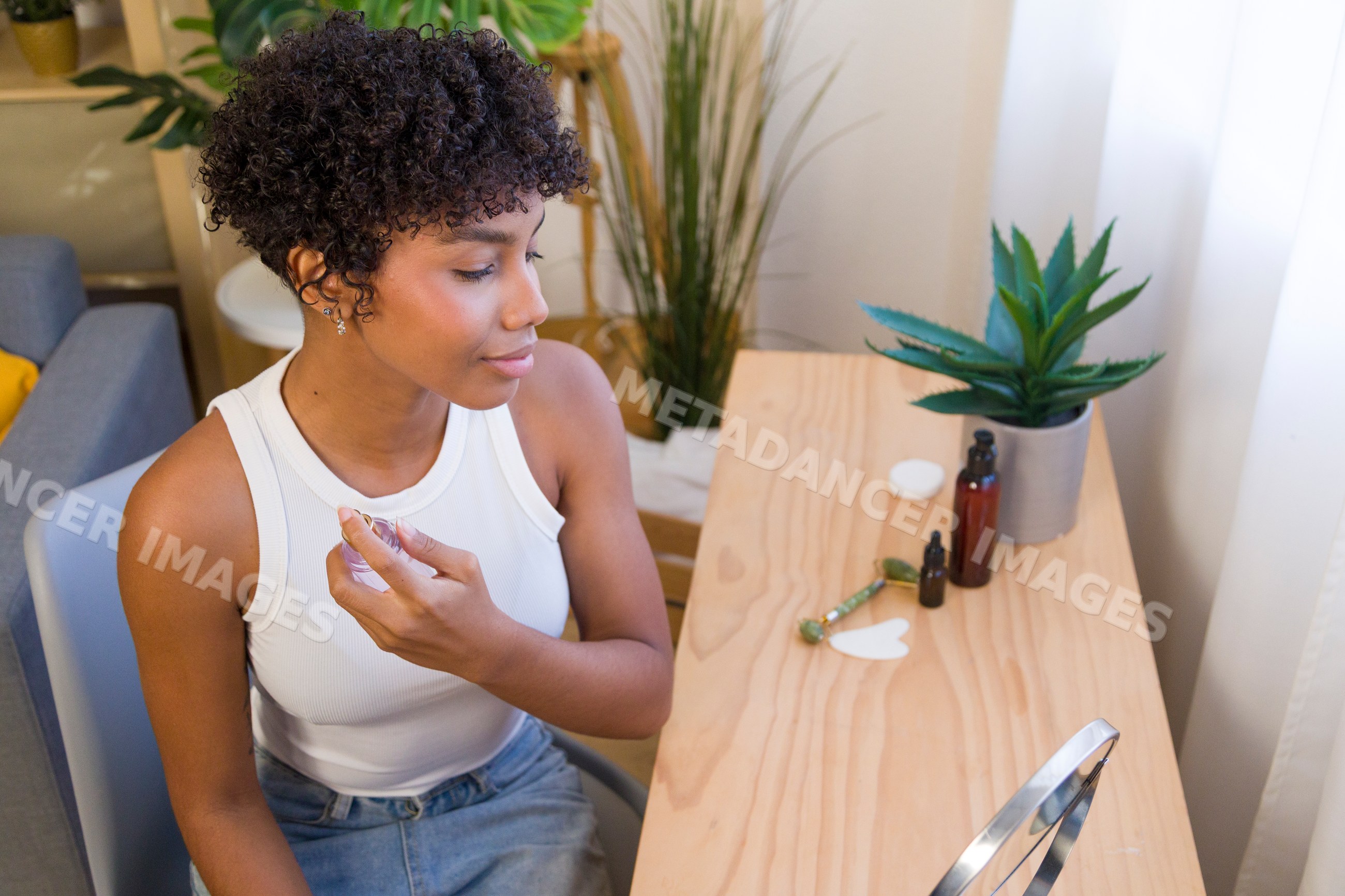 African American woman applying perfume with skincare tools