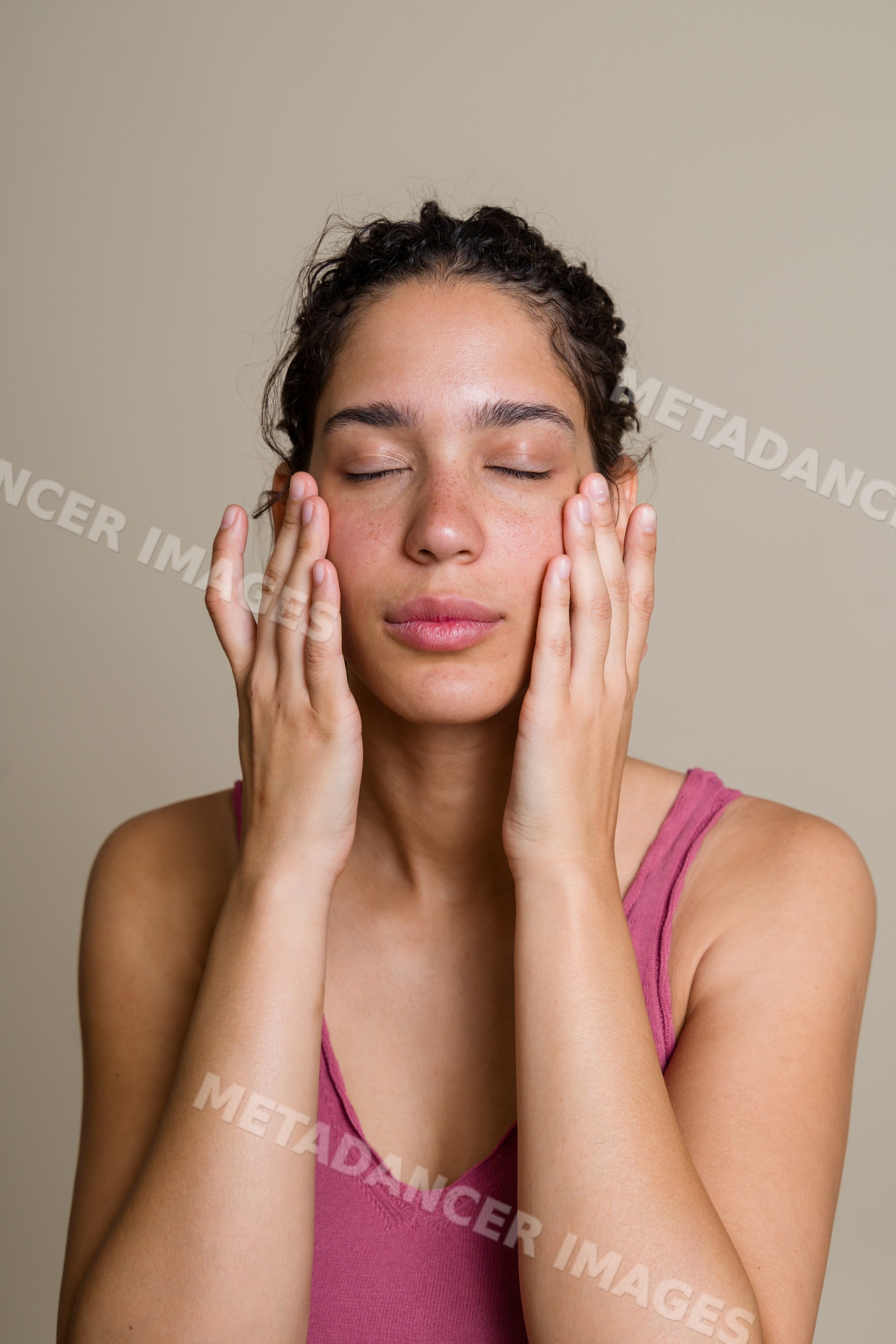 Hispanic woman touching her face in calm skin care moment
