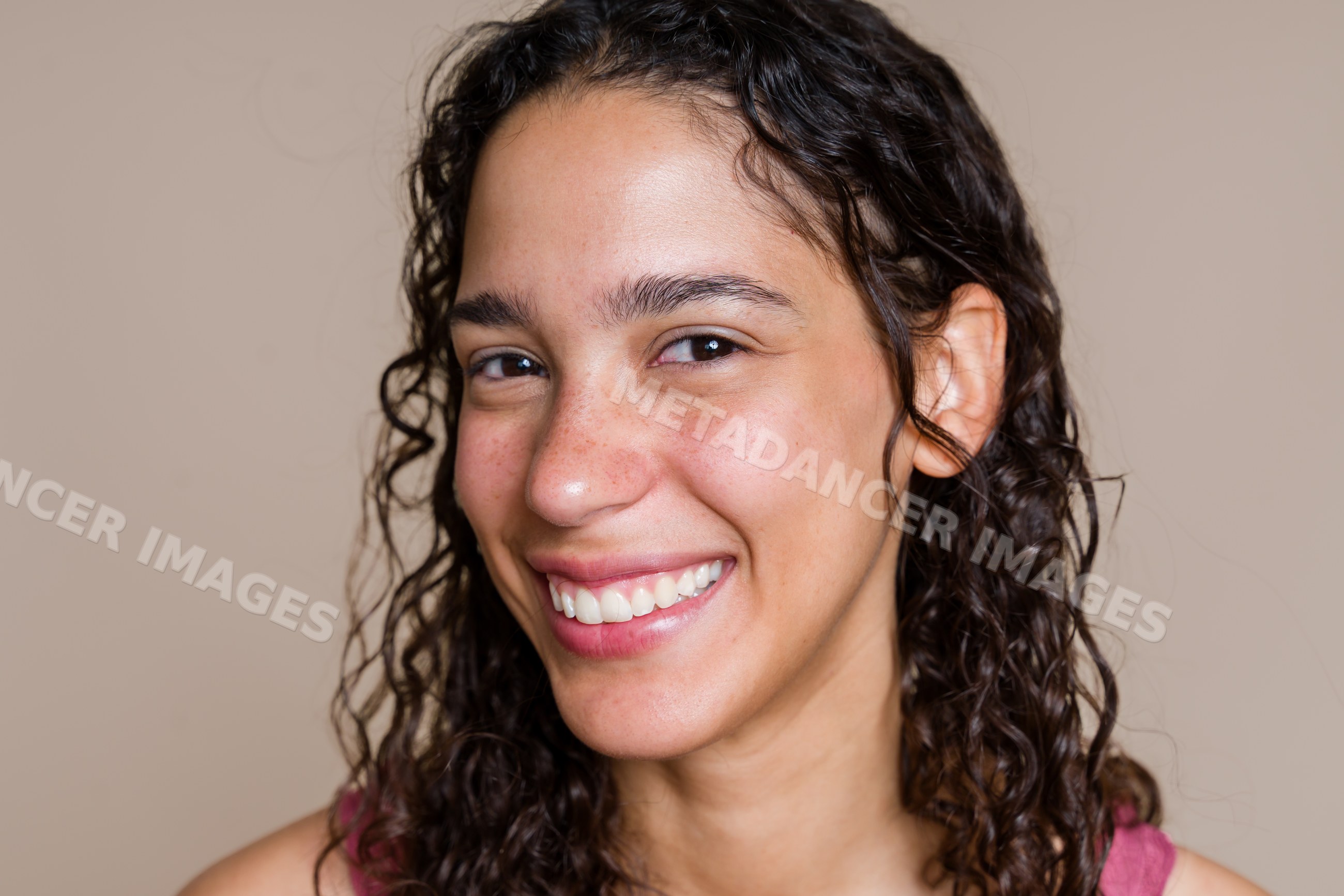 Smiling Hispanic woman with curly hair in a close-up portrait