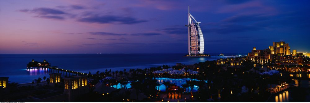 The burj al arab hotel illuminated at night along dubai's persian gulf