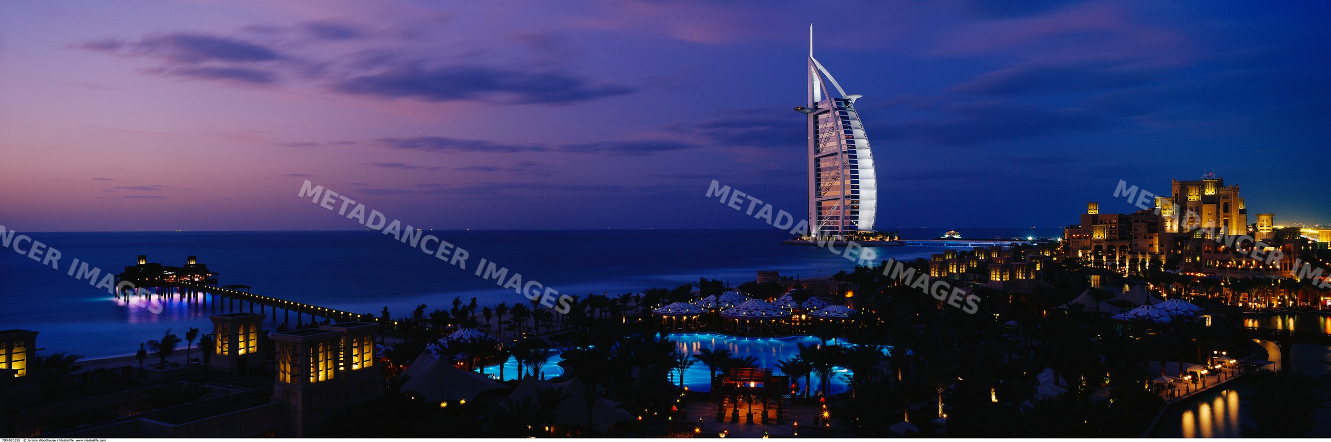 The burj al arab hotel illuminated at night along dubai's persian gulf