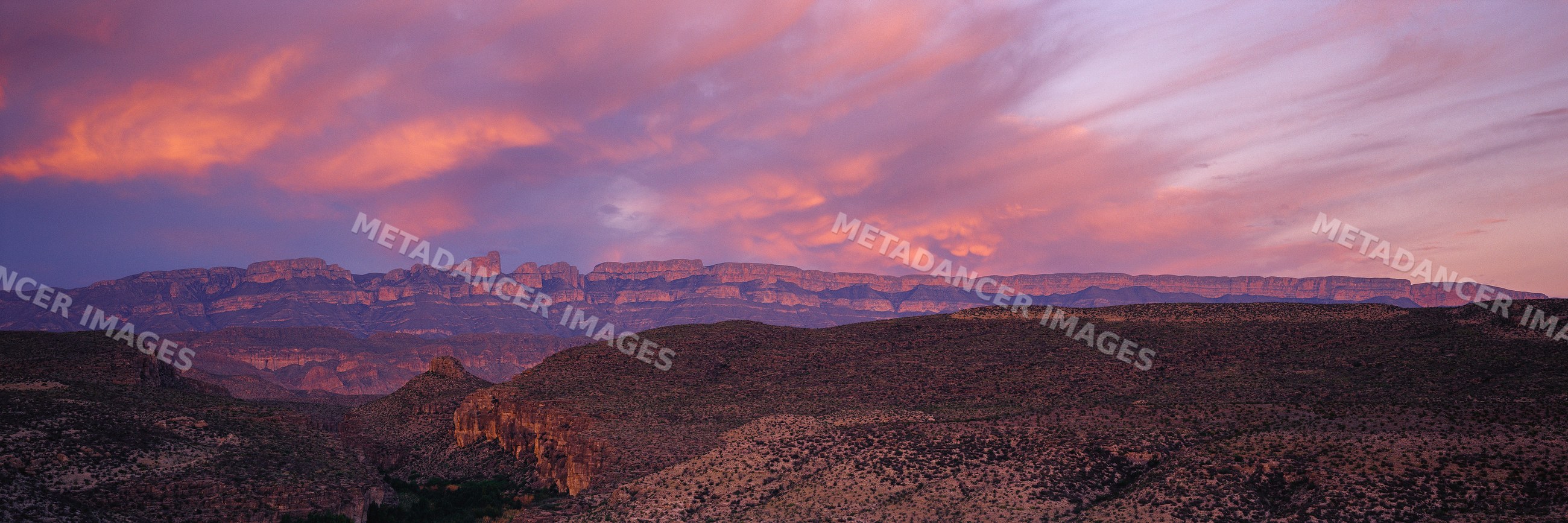Sunset sky over rugged mountains and arid desert landscape