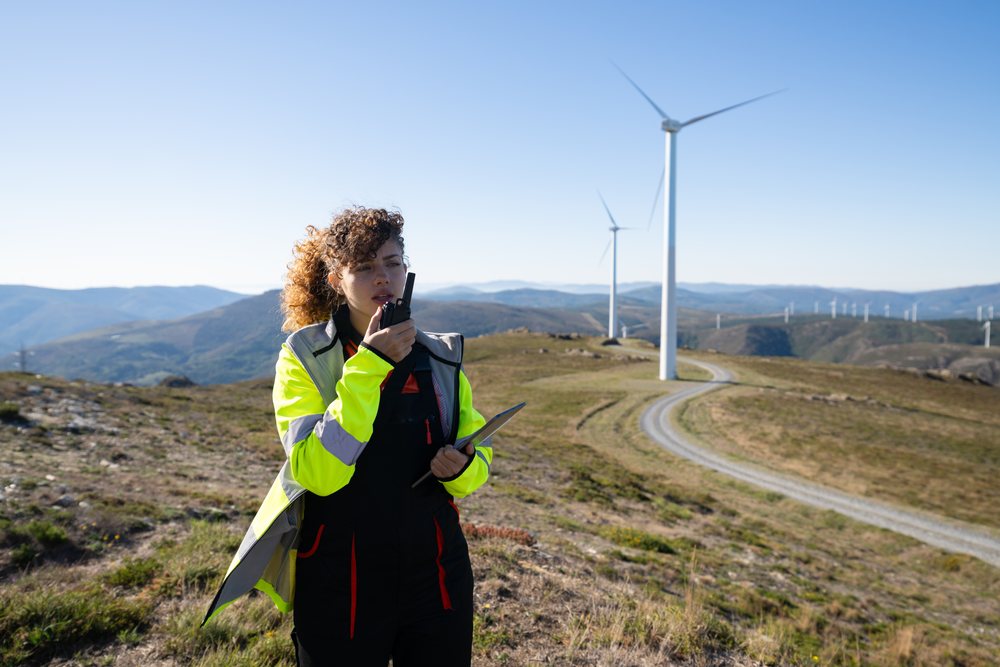 White woman communicating with tablet at wind farm in Galicia, Spain