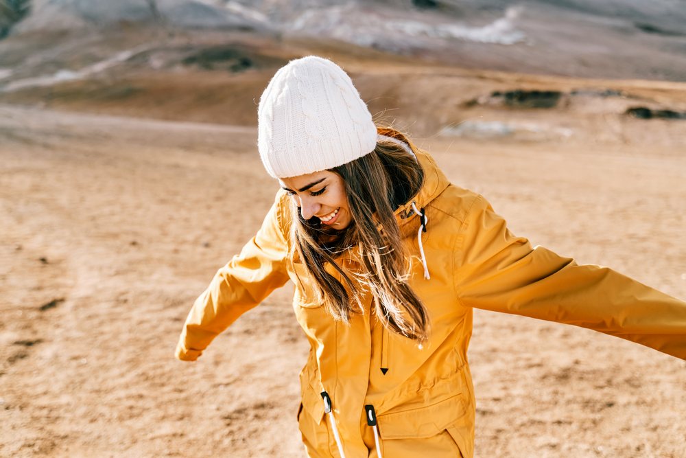 A white woman joyfully stretches her arms outdoors