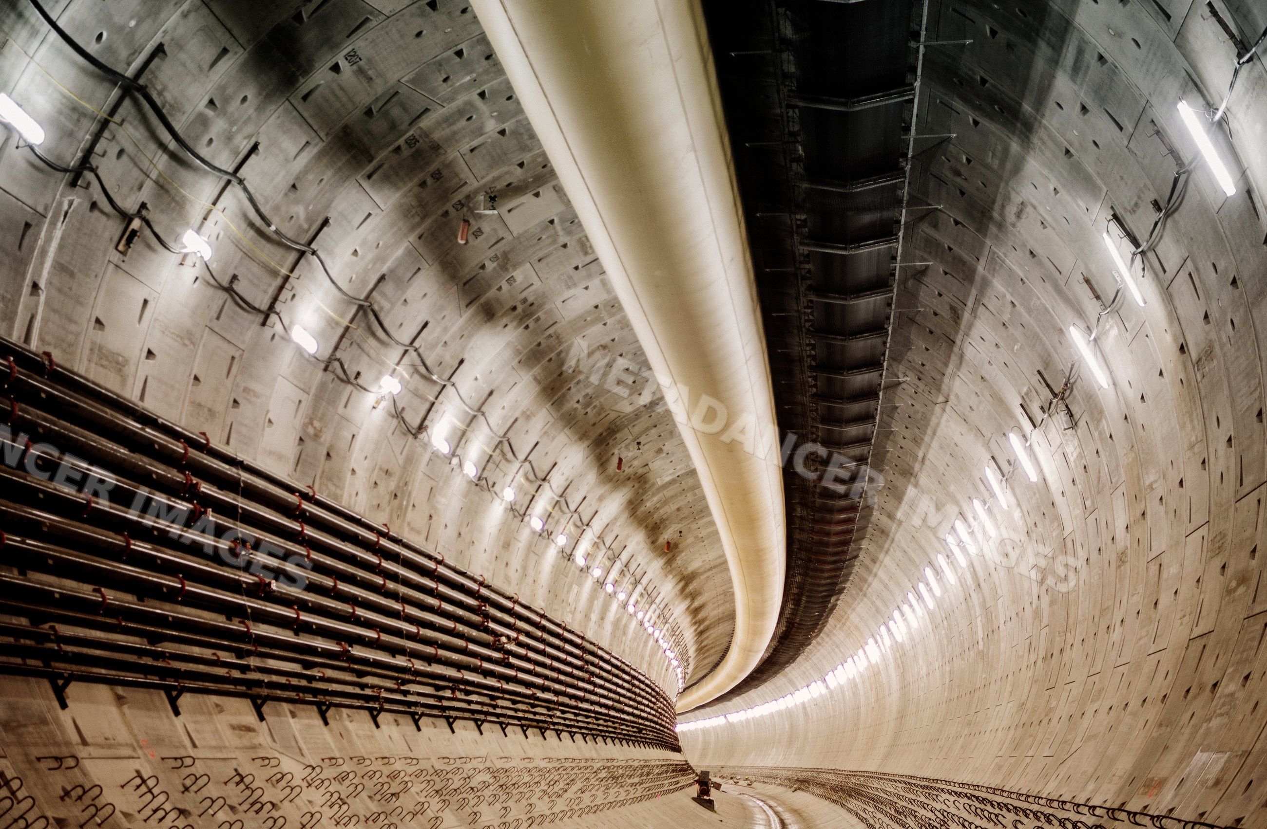 Interior of a large curved tunnel with pipes installed during drilling