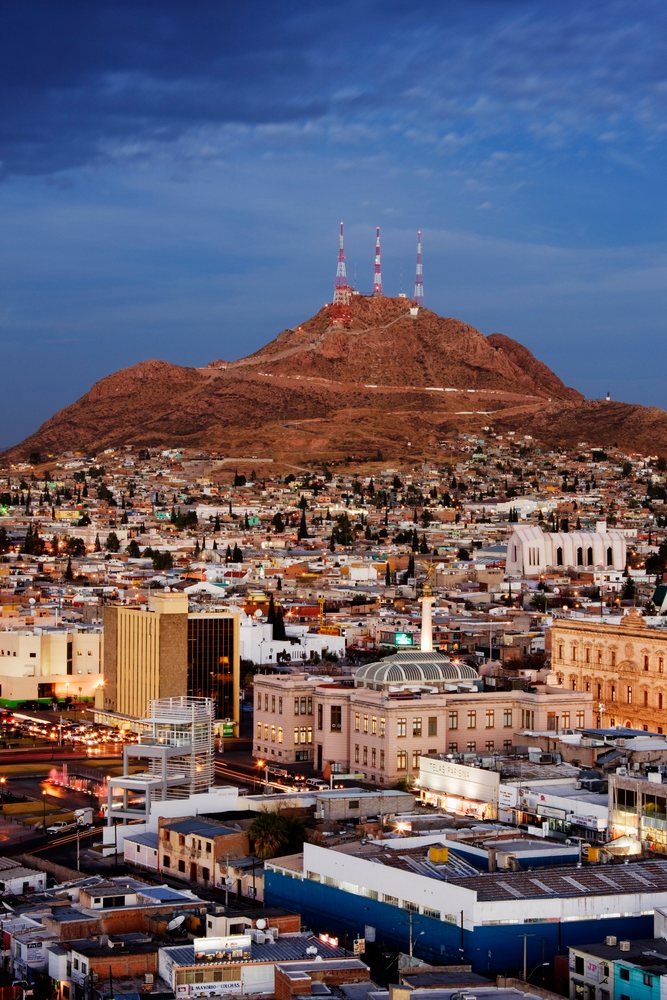 Chihuahua cityscape with communication towers on mountain at dusk