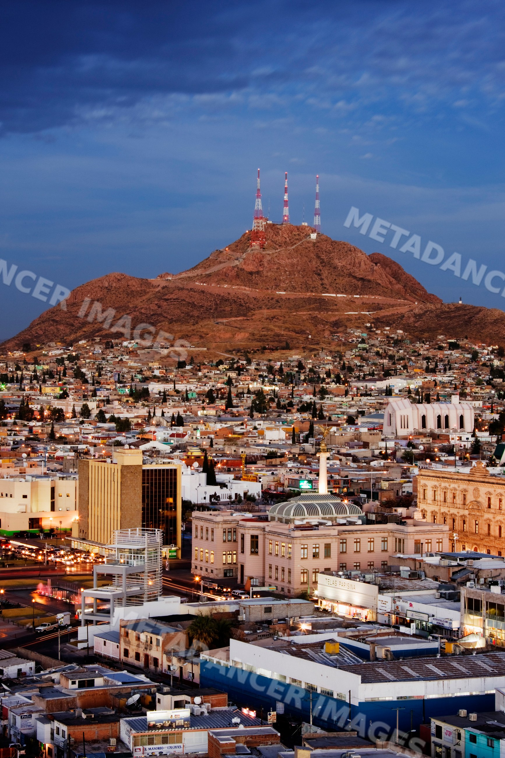 Chihuahua cityscape with communication towers on mountain at dusk