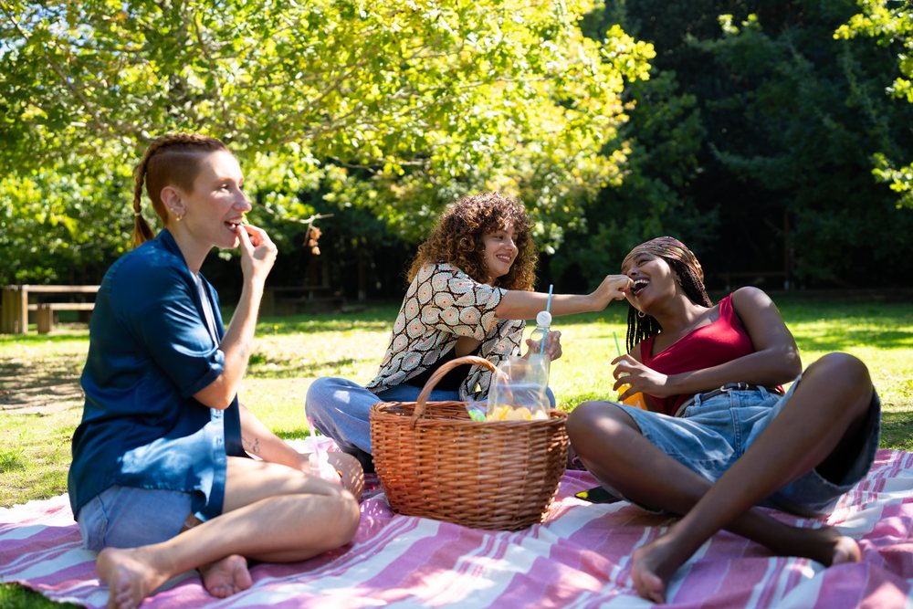 Friends sharing food and drinks during a sunny park picnic