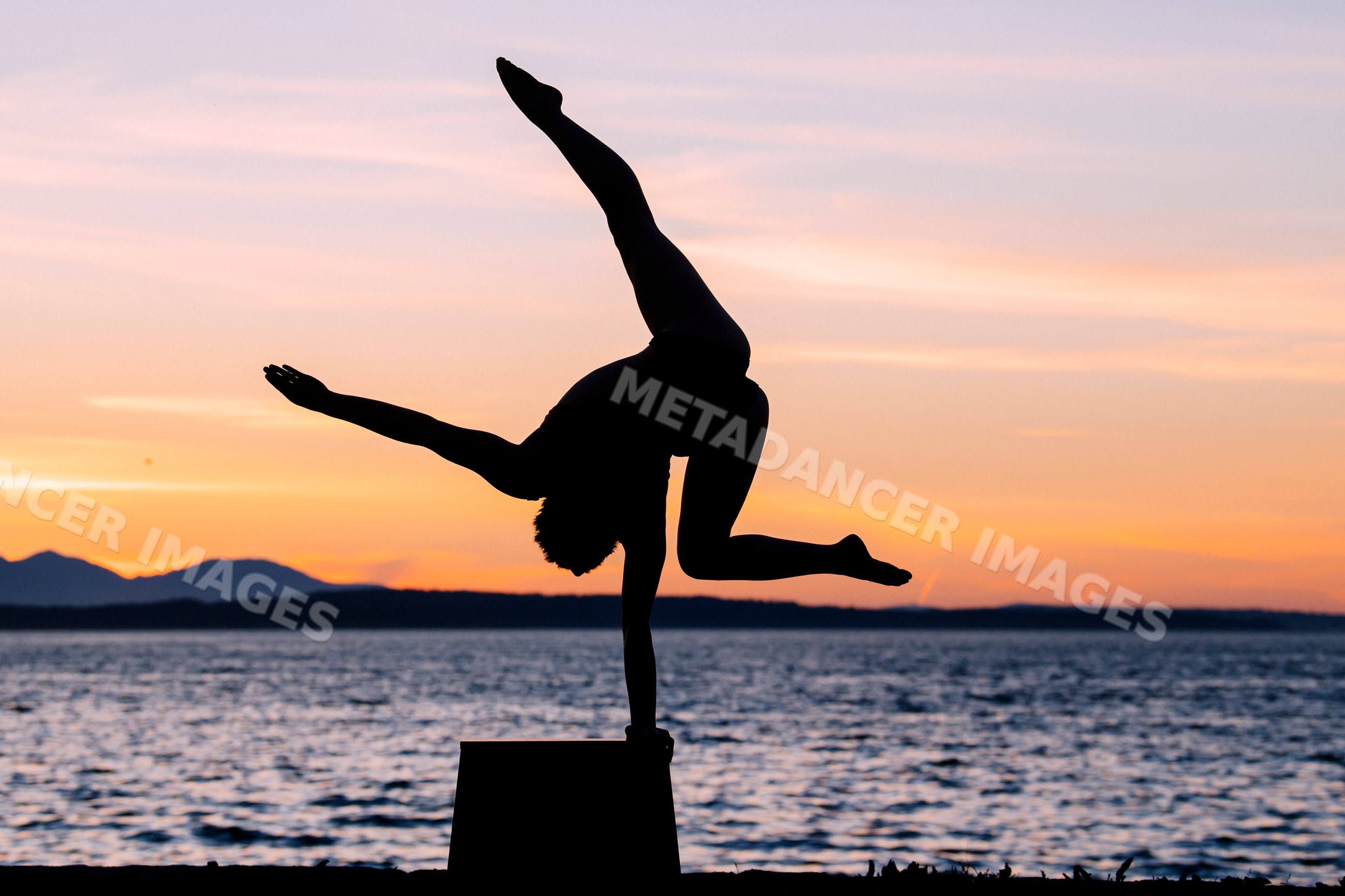 White person performing one-handed handstand silhouette