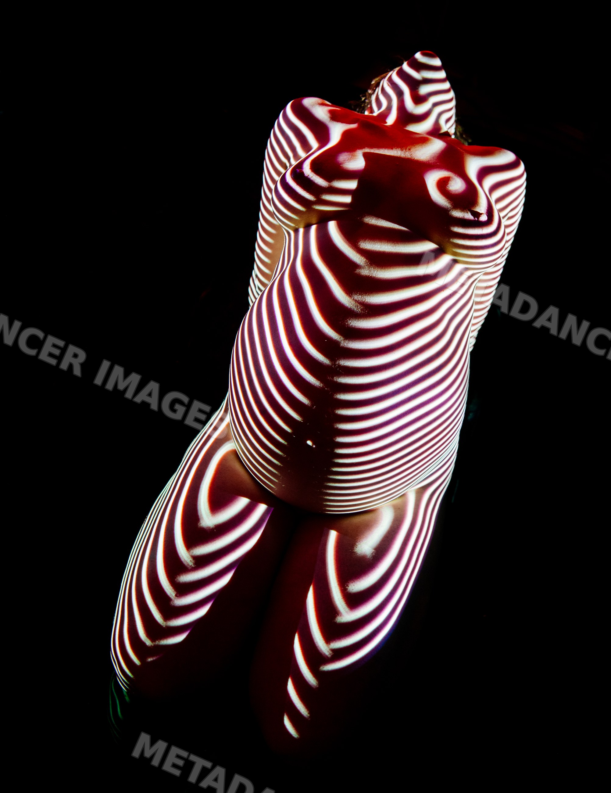Pregnant white woman kneeling with striped light projection