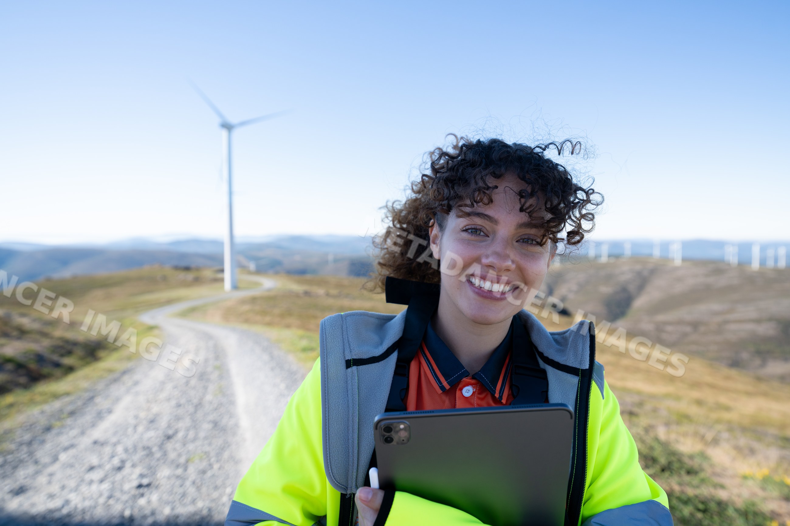 White woman holding tablet at wind farm on rural hills in Galicia
