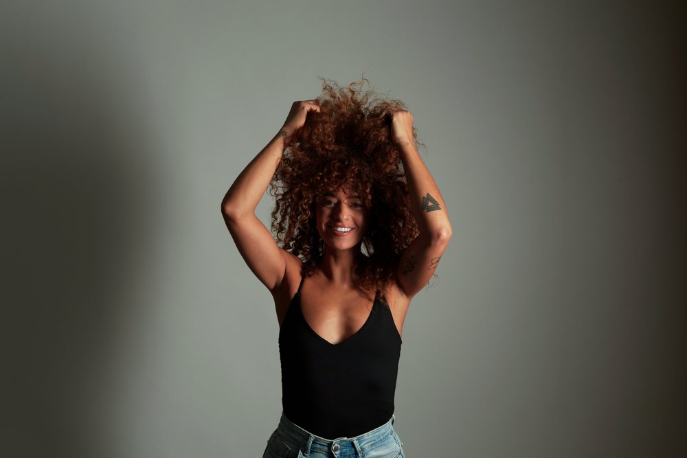 Hispanic woman with curly red hair posing and smiling