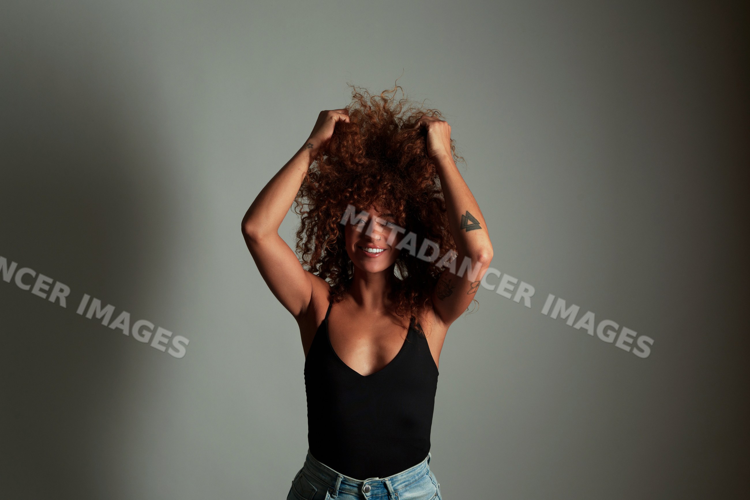Hispanic woman with curly red hair posing and smiling