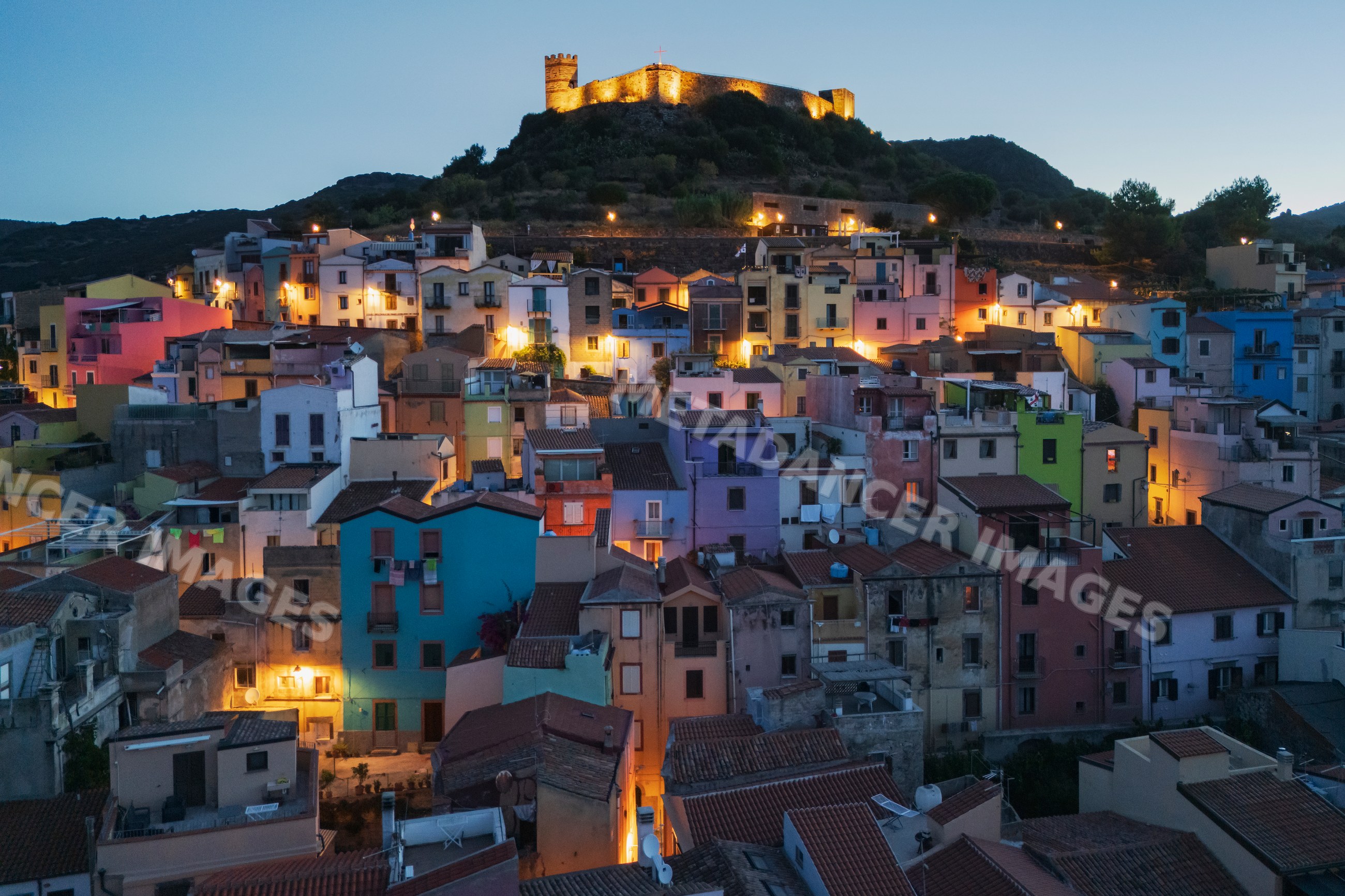 Old town of bosa with illuminated hilltop castle at dawn in sardinia