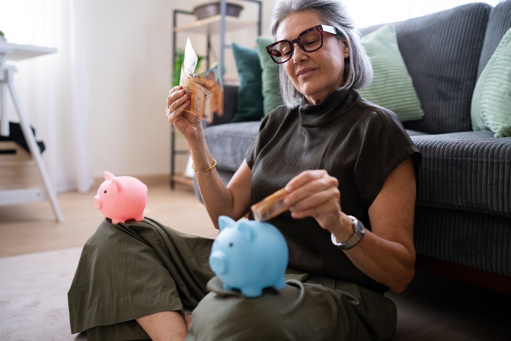 White woman saving money with piggy banks at home in Spain