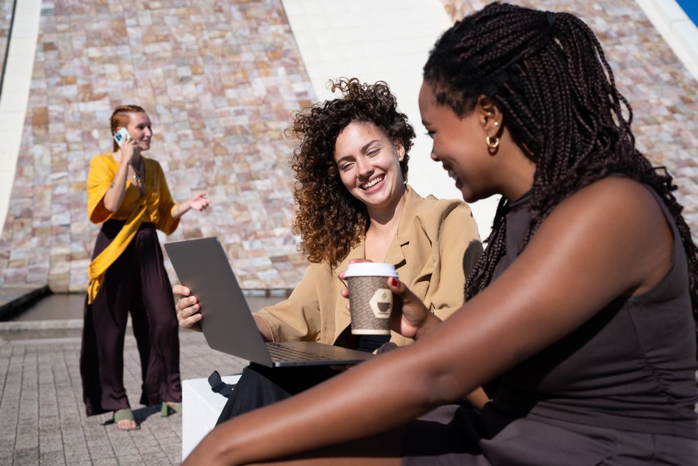 Three African American and white women using laptop, coffee