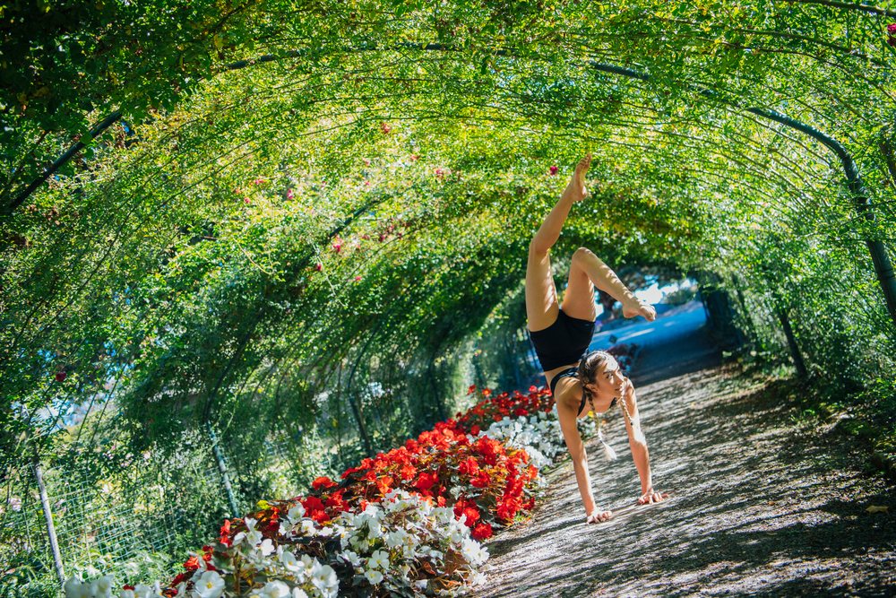 Contortionist performing handstand under flowered garden archway