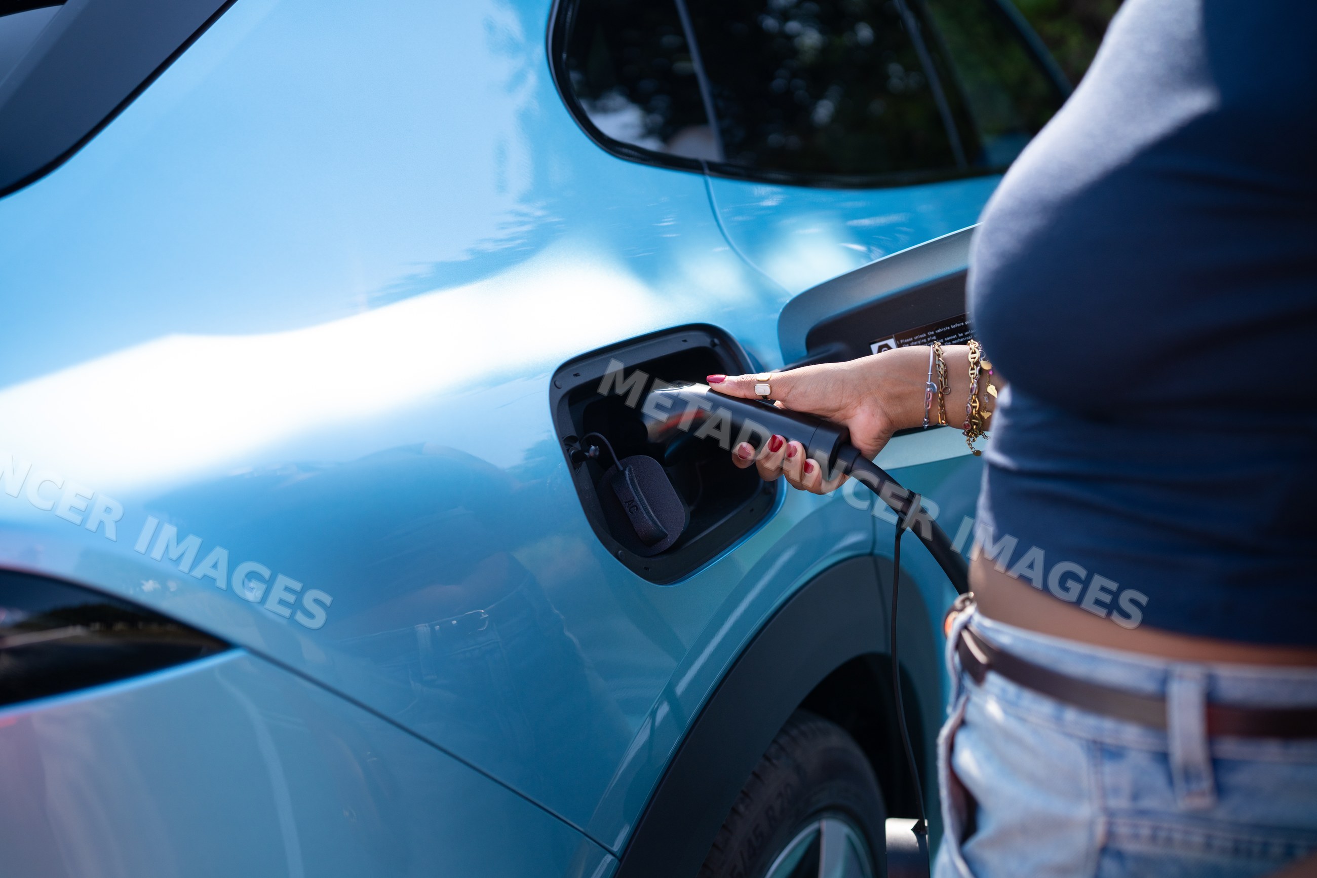 A African American woman charging an electric vehicle outdoors