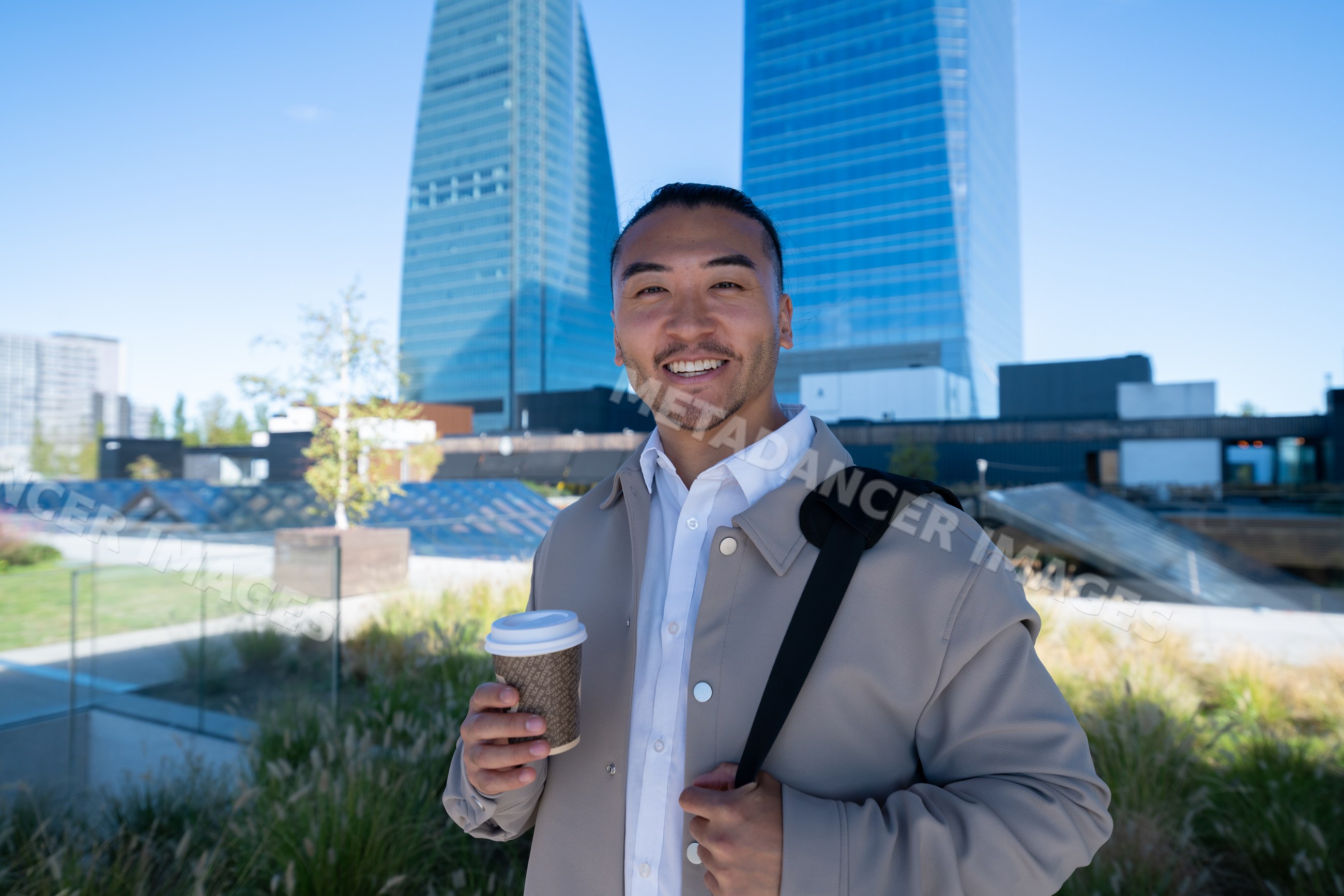 Man holding coffee cup outdoors near modern city buildings in Madrid