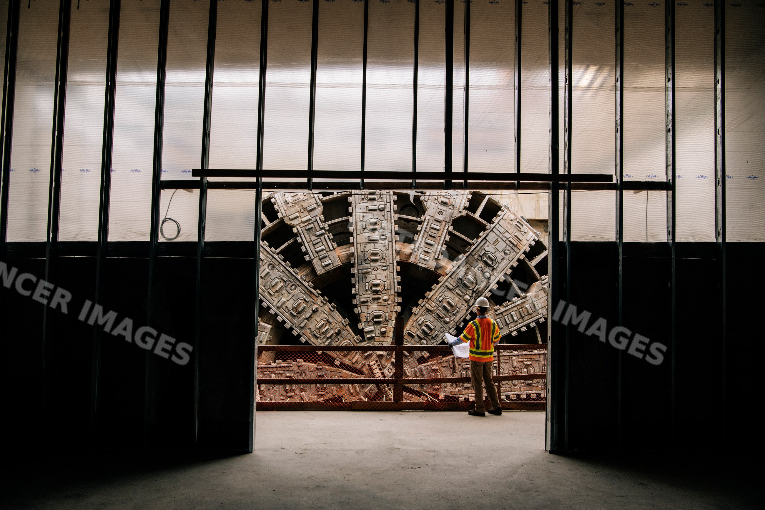 A construction white worker inspects a large tunnel boring machine