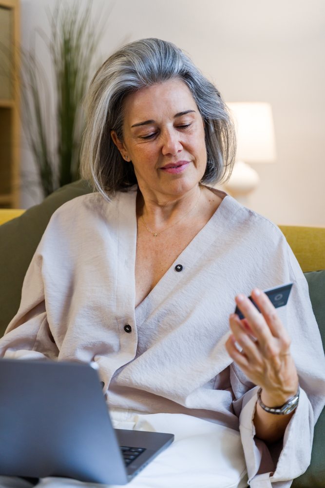 White woman using credit card and laptop on couch at home in Spain
