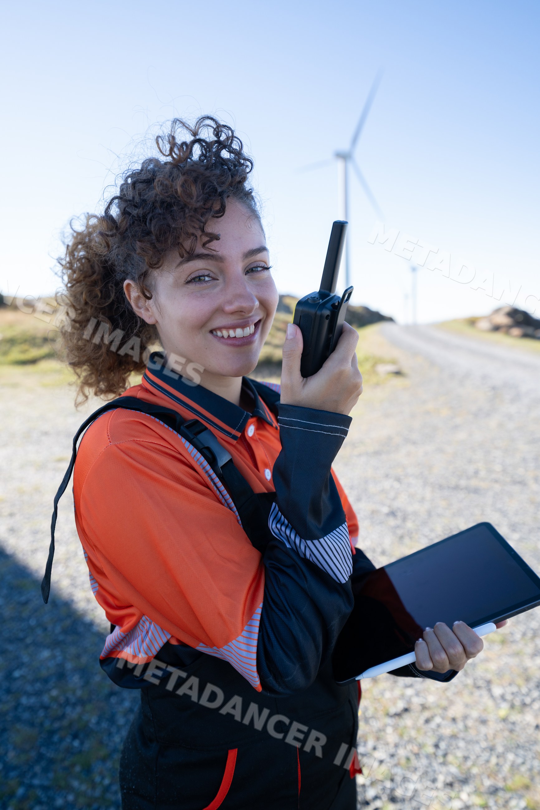 White woman communicating with walkie talkie at wind farm in Galicia