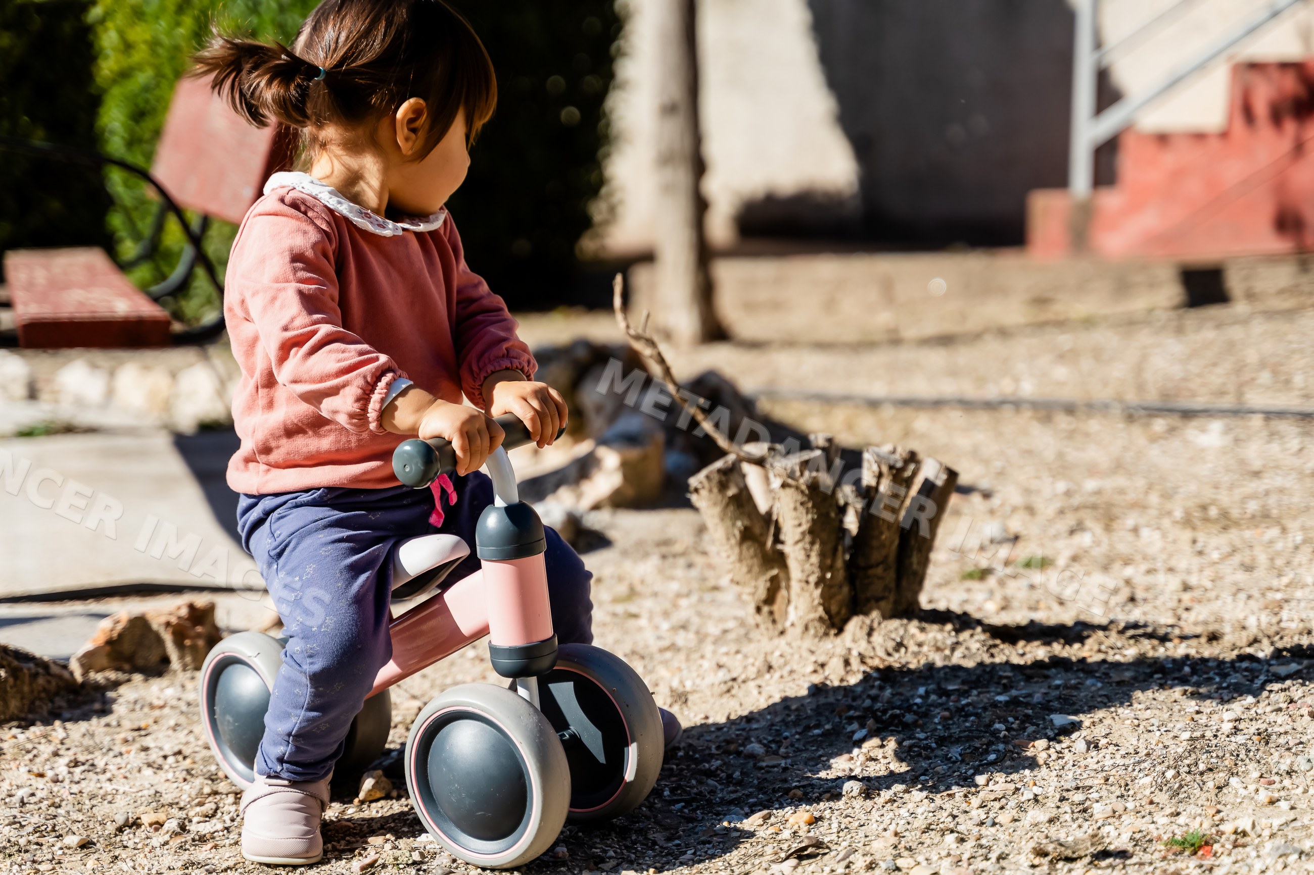 Toddler white girl riding balance bike outdoors in a park