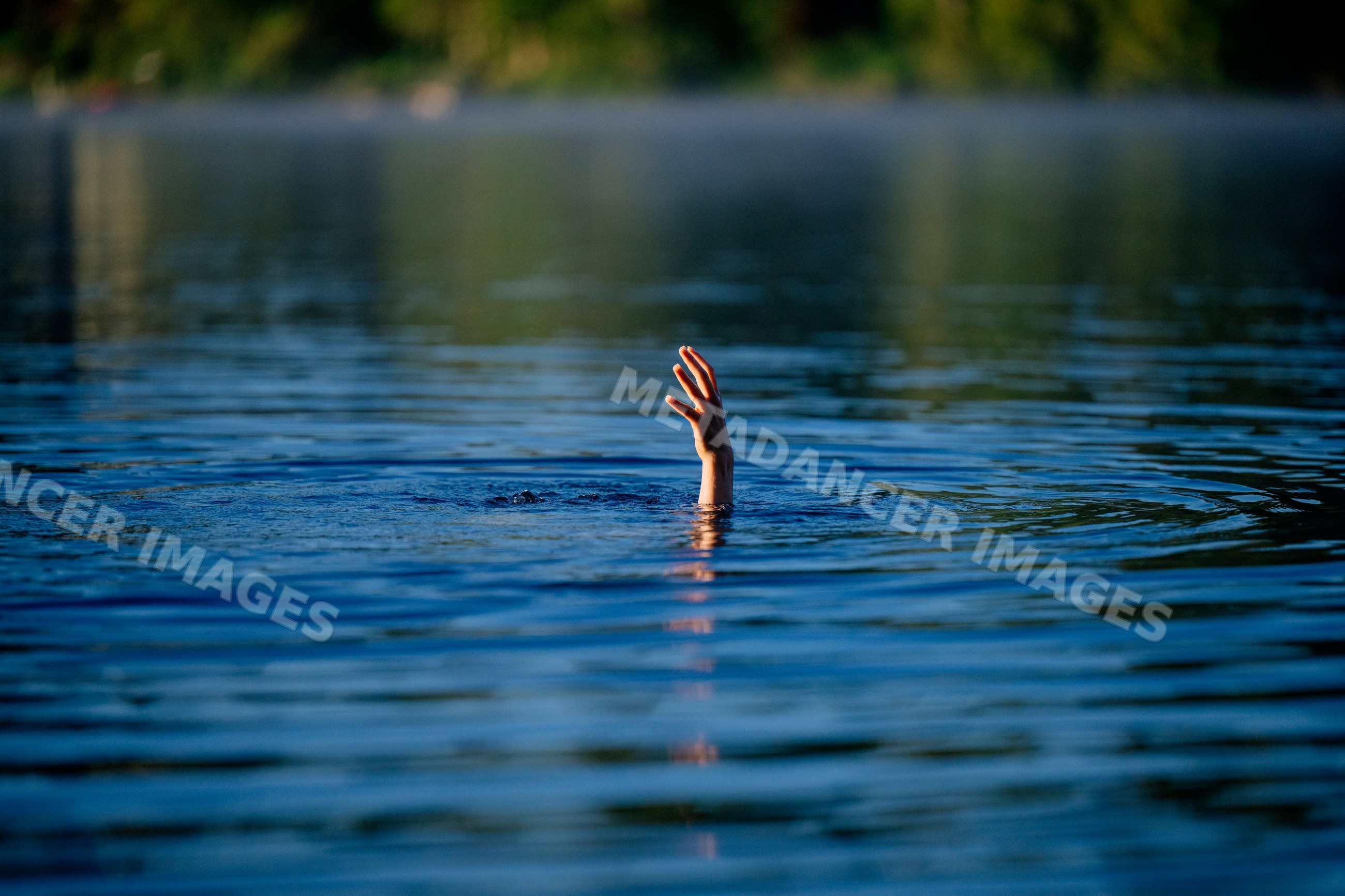 Hand reaching out of water as white person struggles to stay afloat