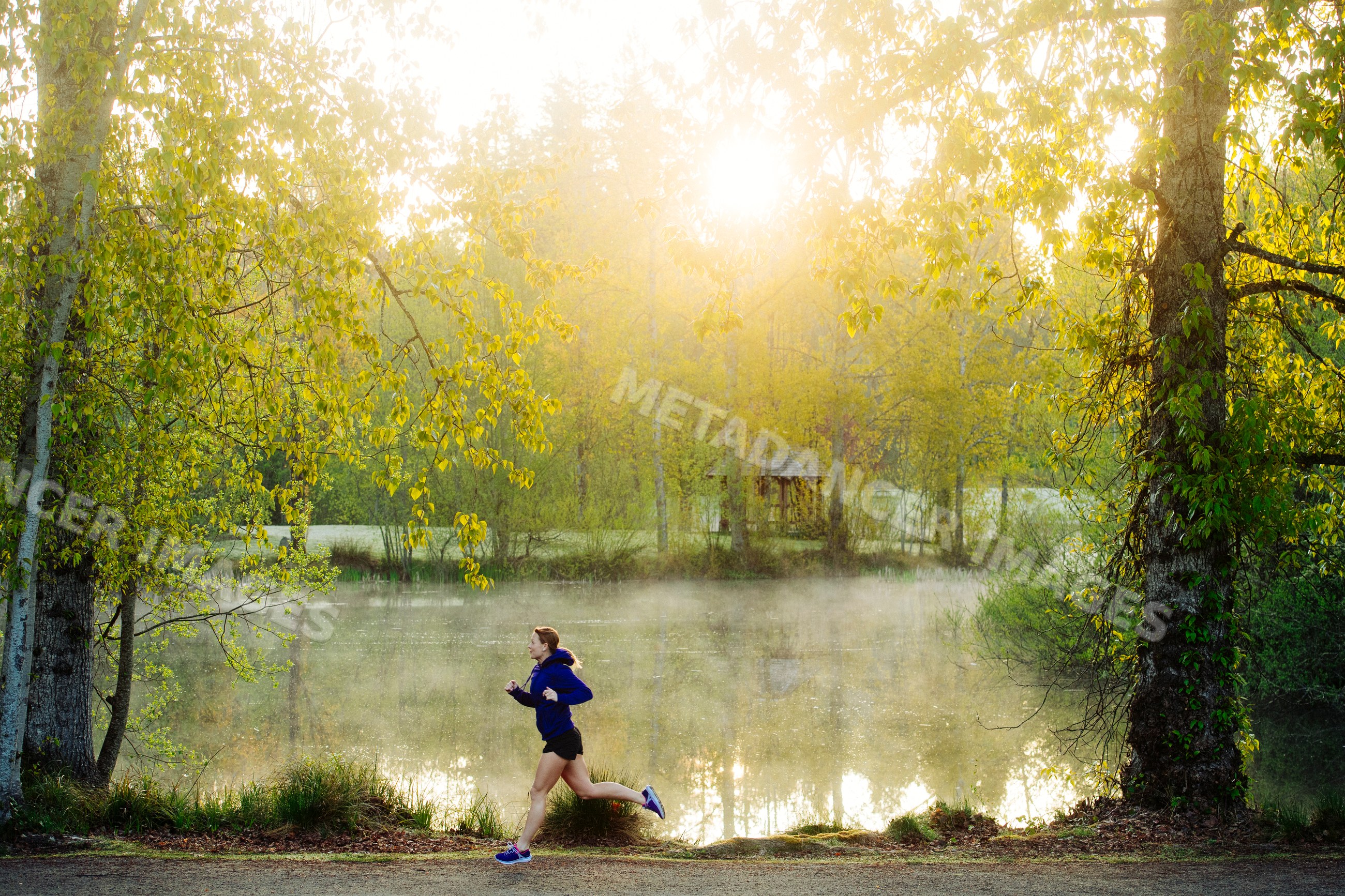 White runner jogging in misty park by lake at sunrise