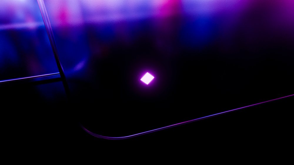 Glowing purple diamond-shaped neon light on reflective black surface