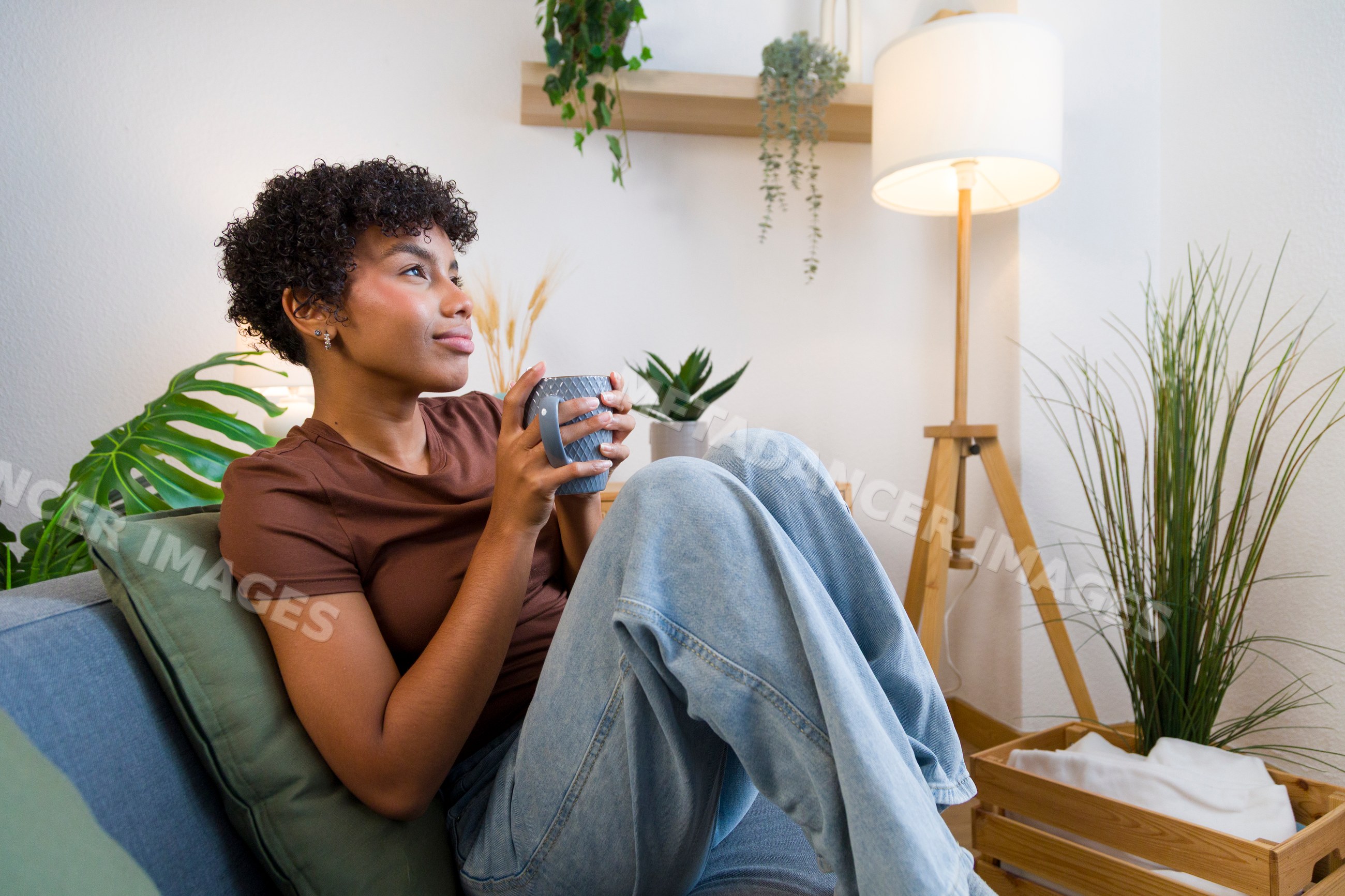Young African American woman relaxing with a mug on sofa