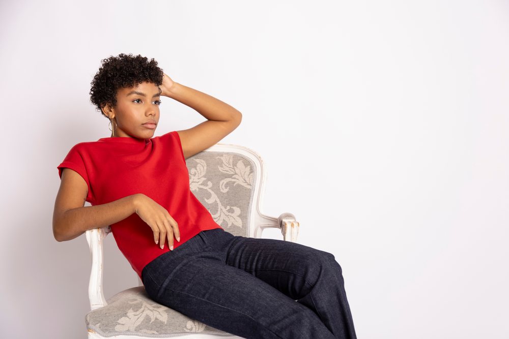 Young Hispanic woman wearing red top seated on elegant chair