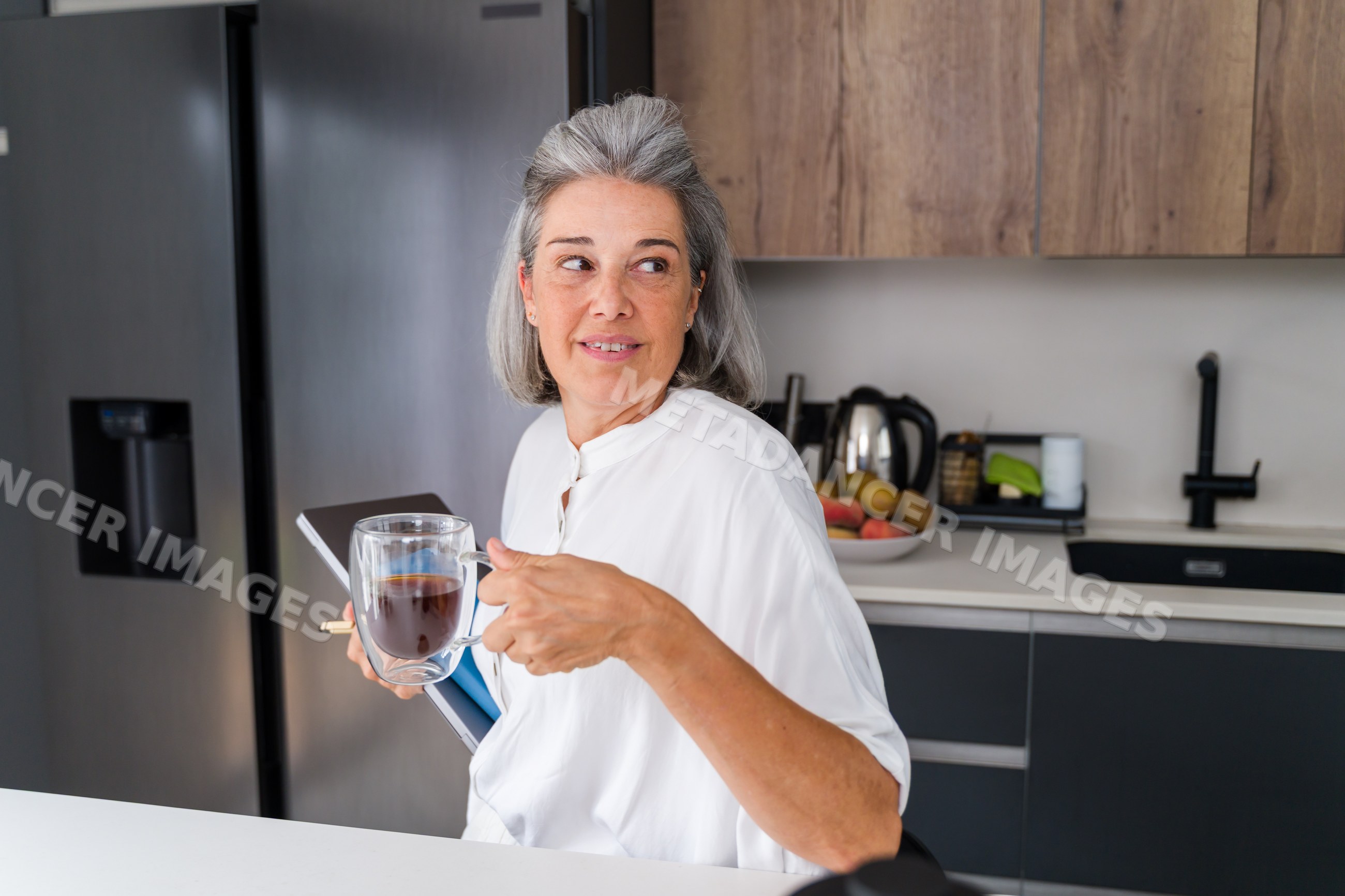 Middle-aged white woman holding coffee mug and tablet