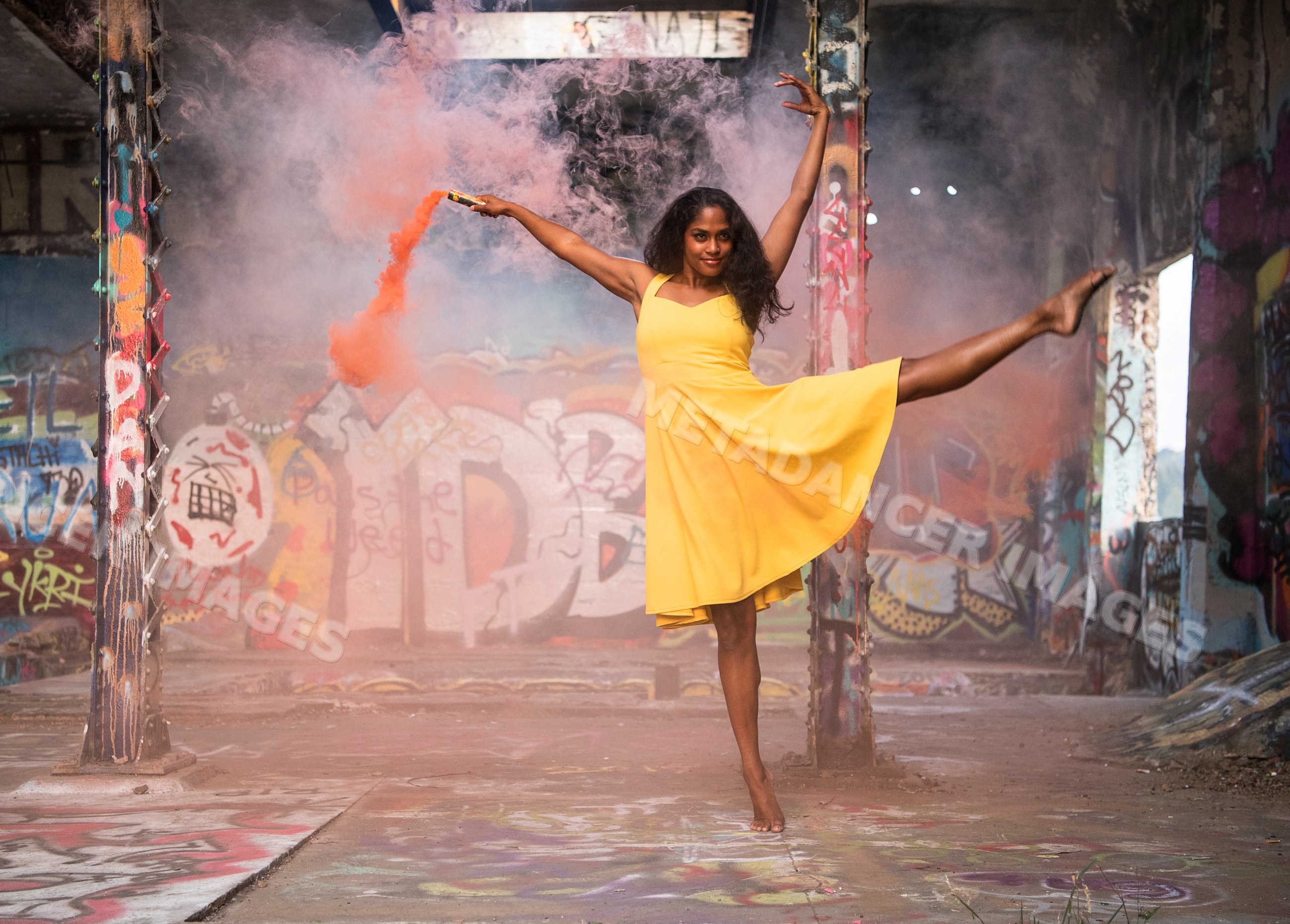 South Asian woman dancing barefoot with smoke flare