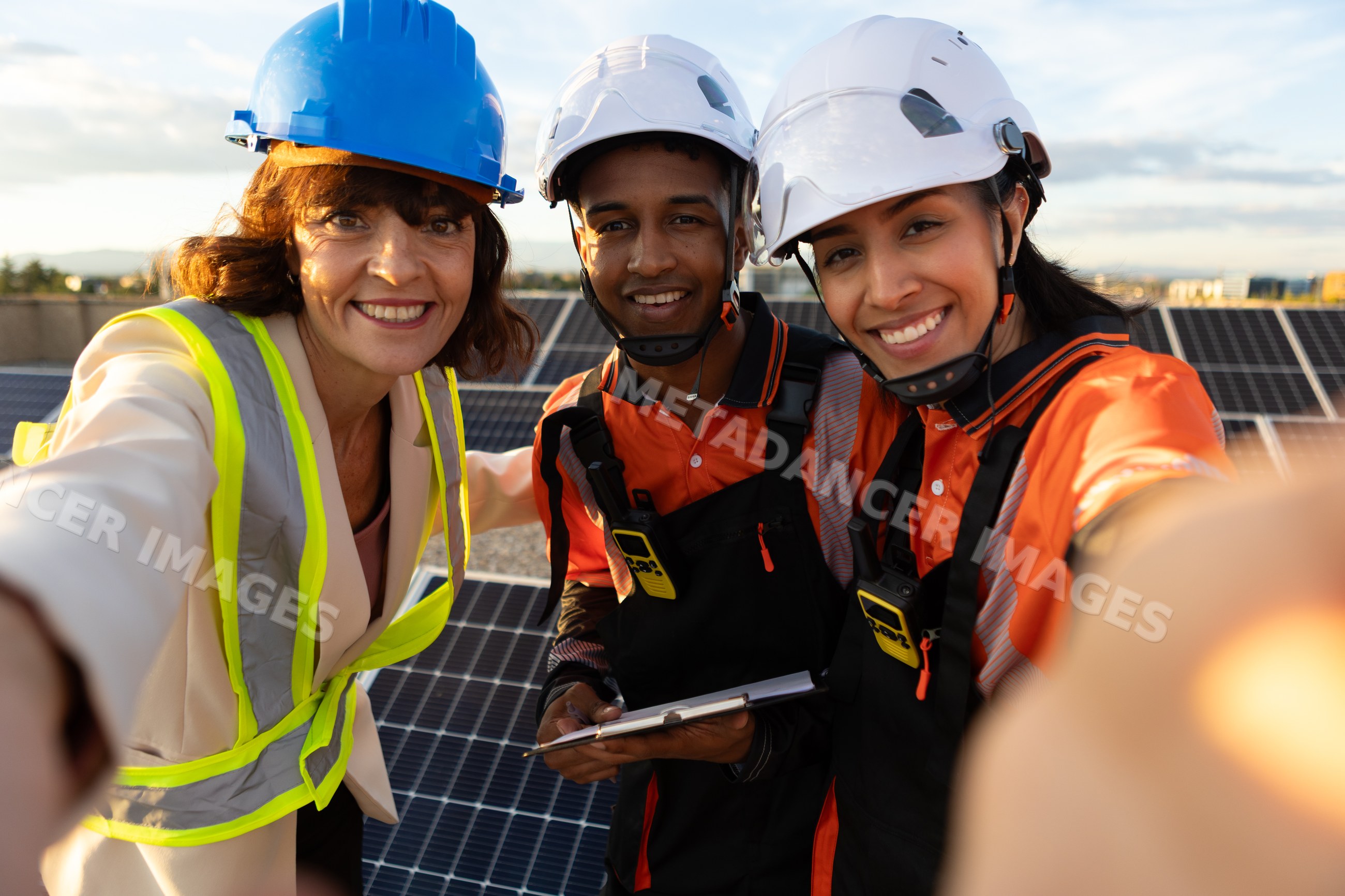 Hispanic and white workers posing on solar panel installation site