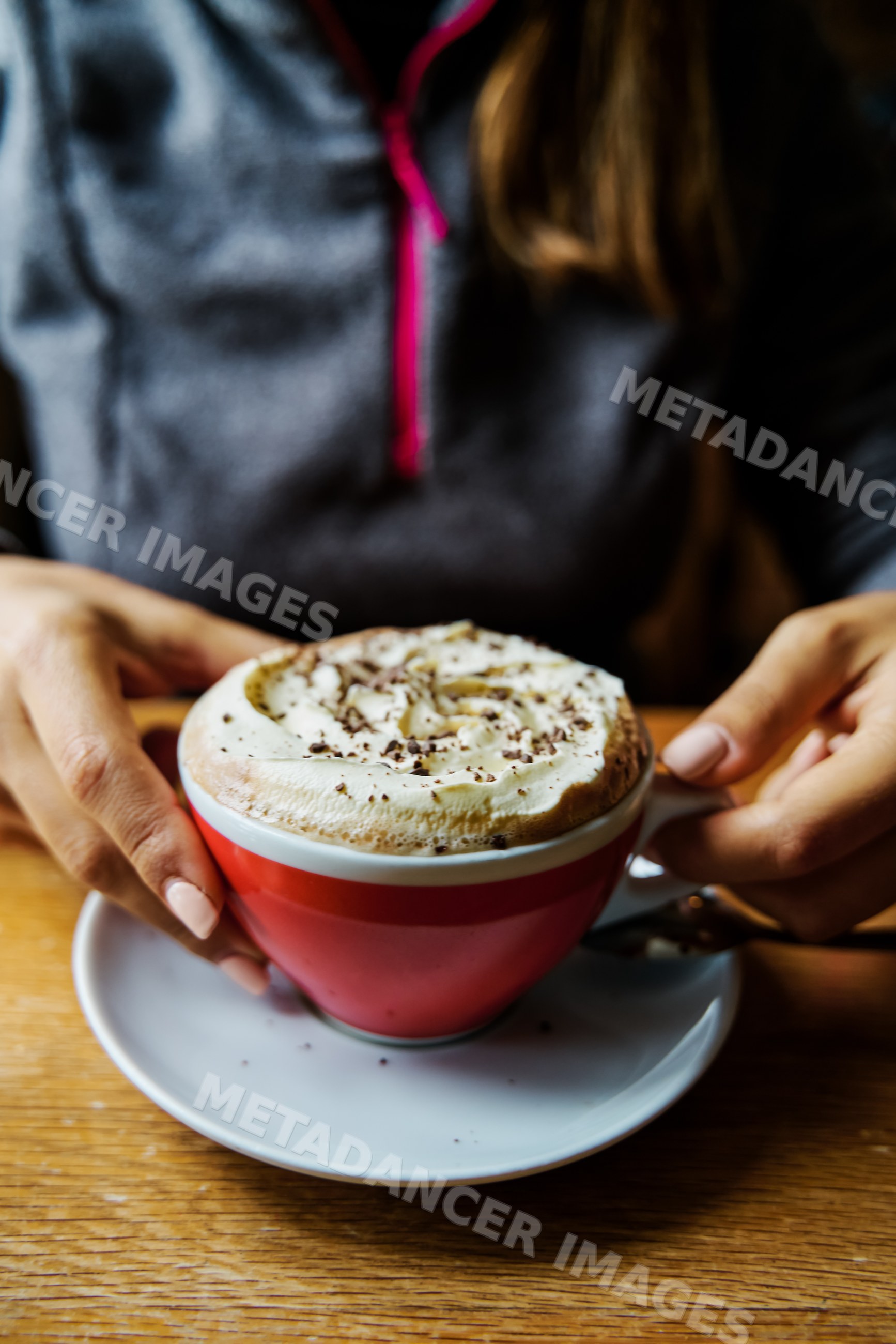 A white woman holds a cup of hot chocolate with whipped cream