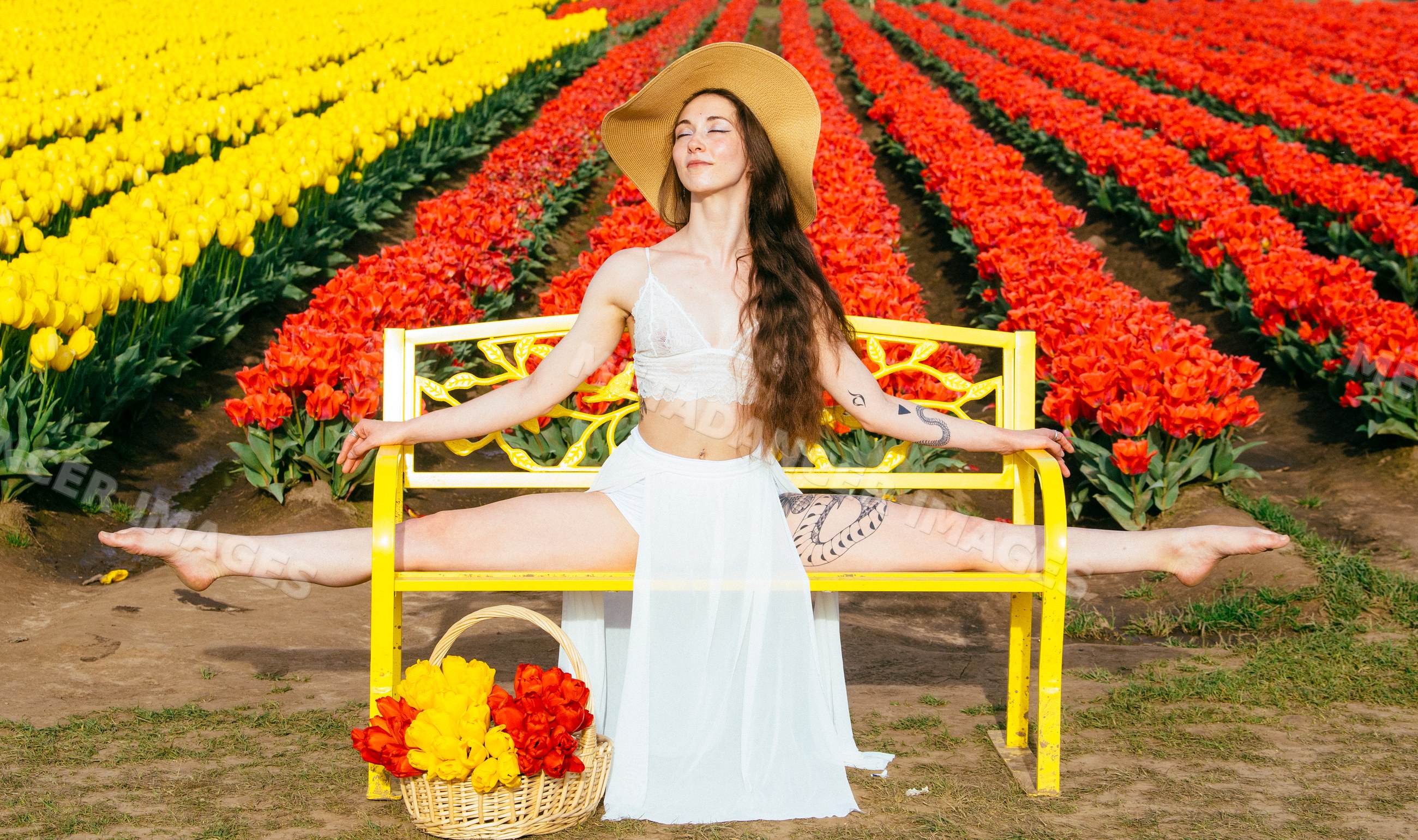 White woman doing split on yellow bench in tulip field