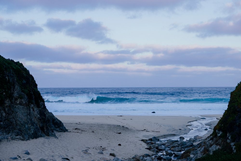 Ocean waves breaking on sandy beach with coastal cliffs