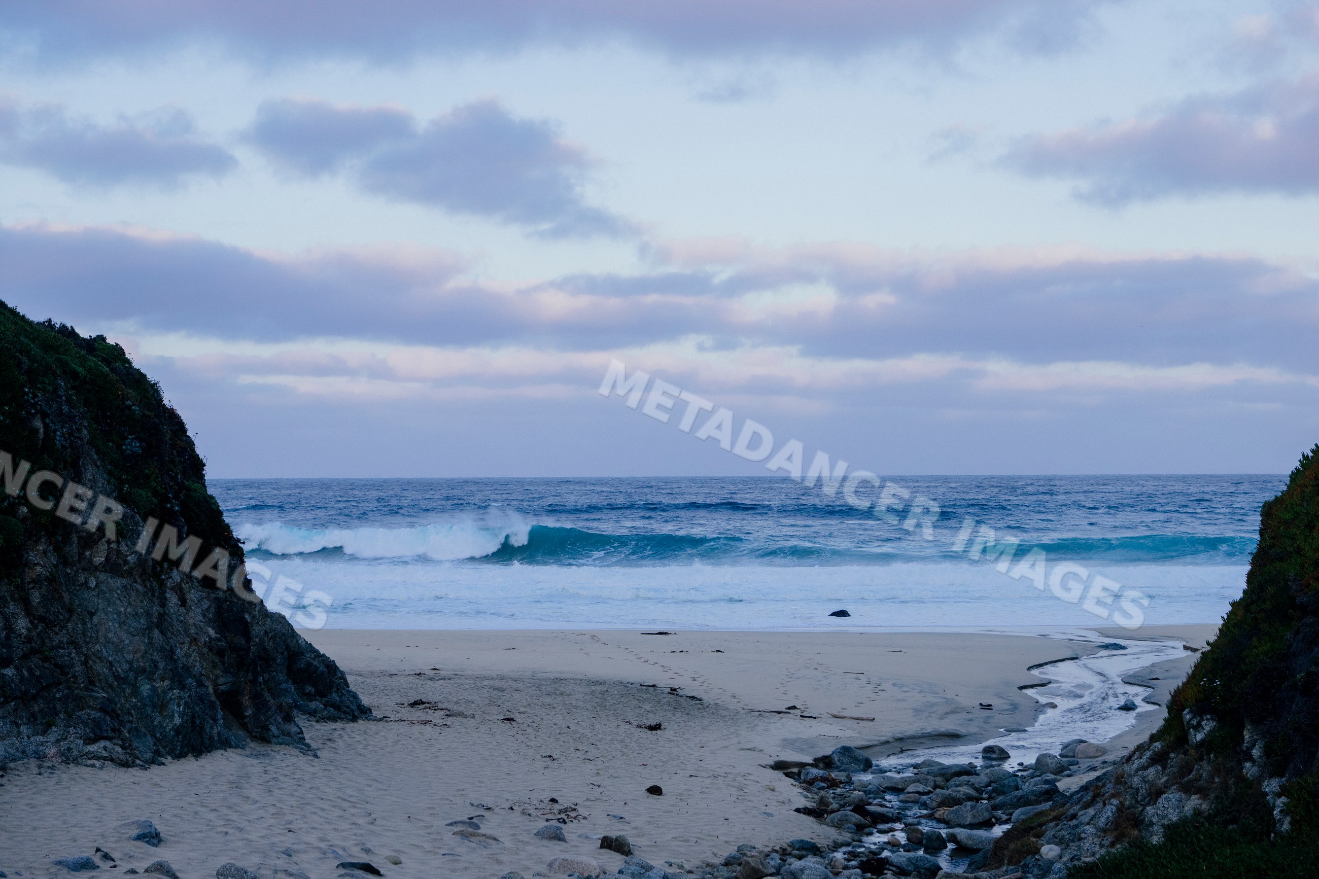 Ocean waves breaking on sandy beach with coastal cliffs