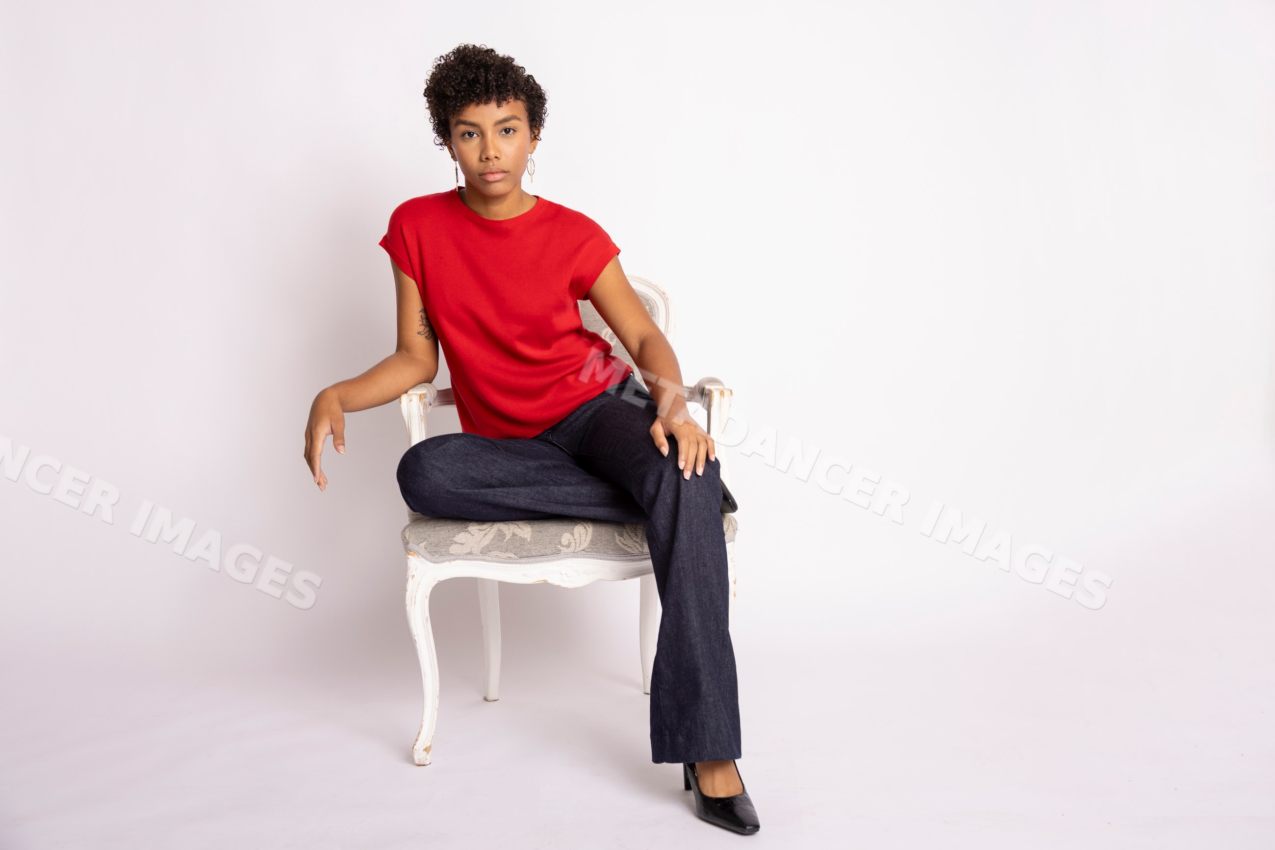 Hispanic woman sitting on vintage carved chair wearing red shirt