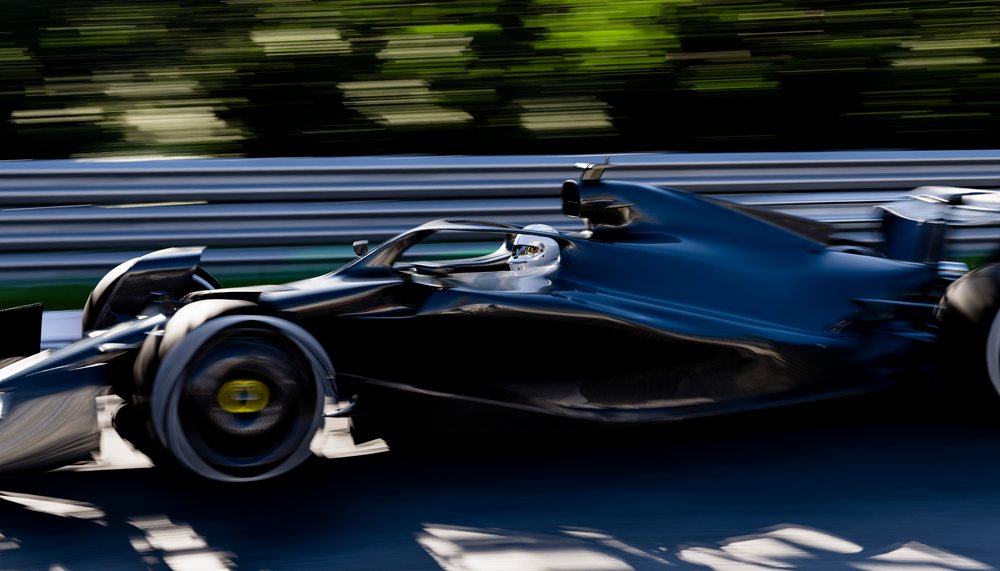 A black race car driven at high speed on a professional race track