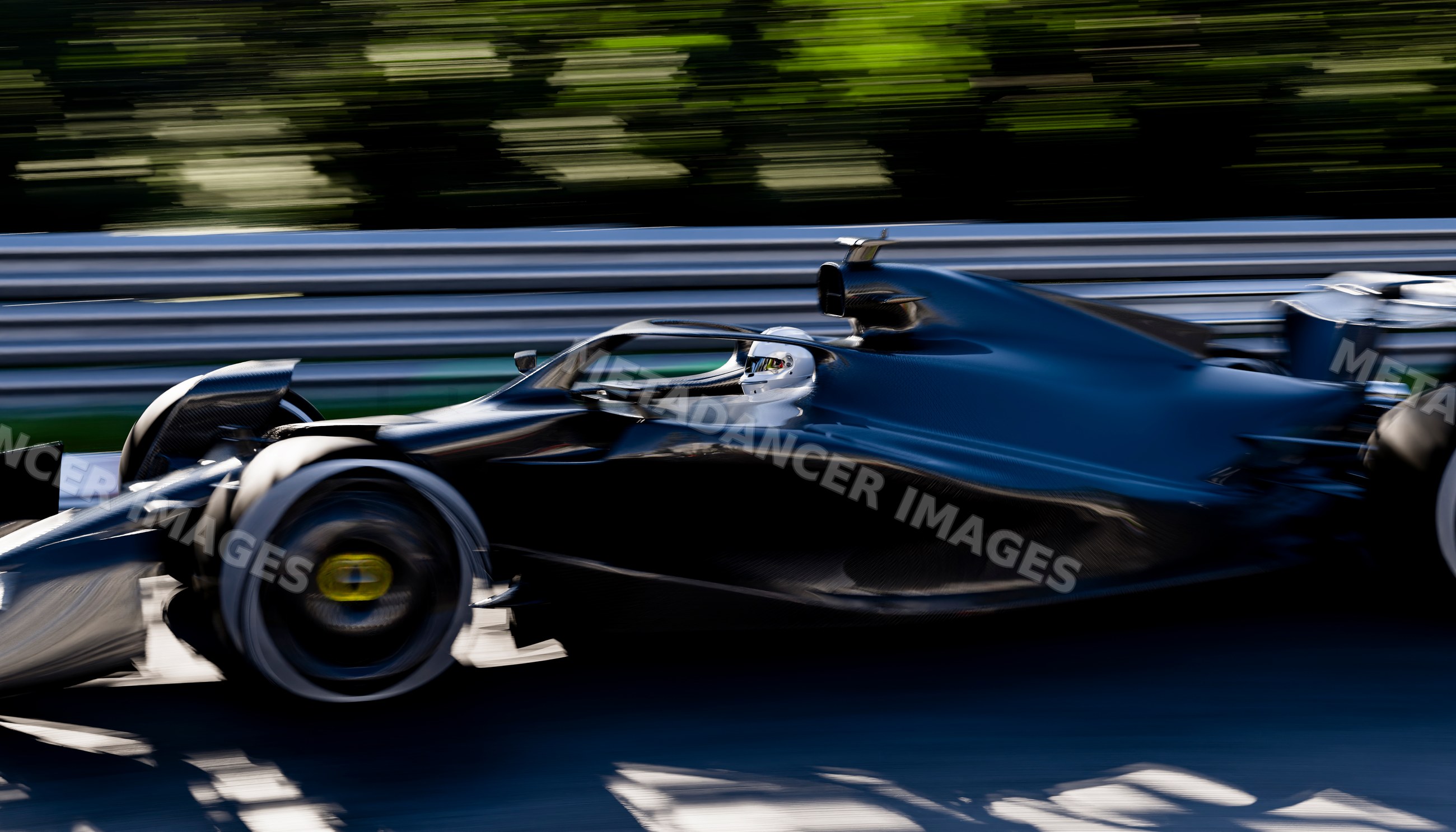 A black race car driven at high speed on a professional race track