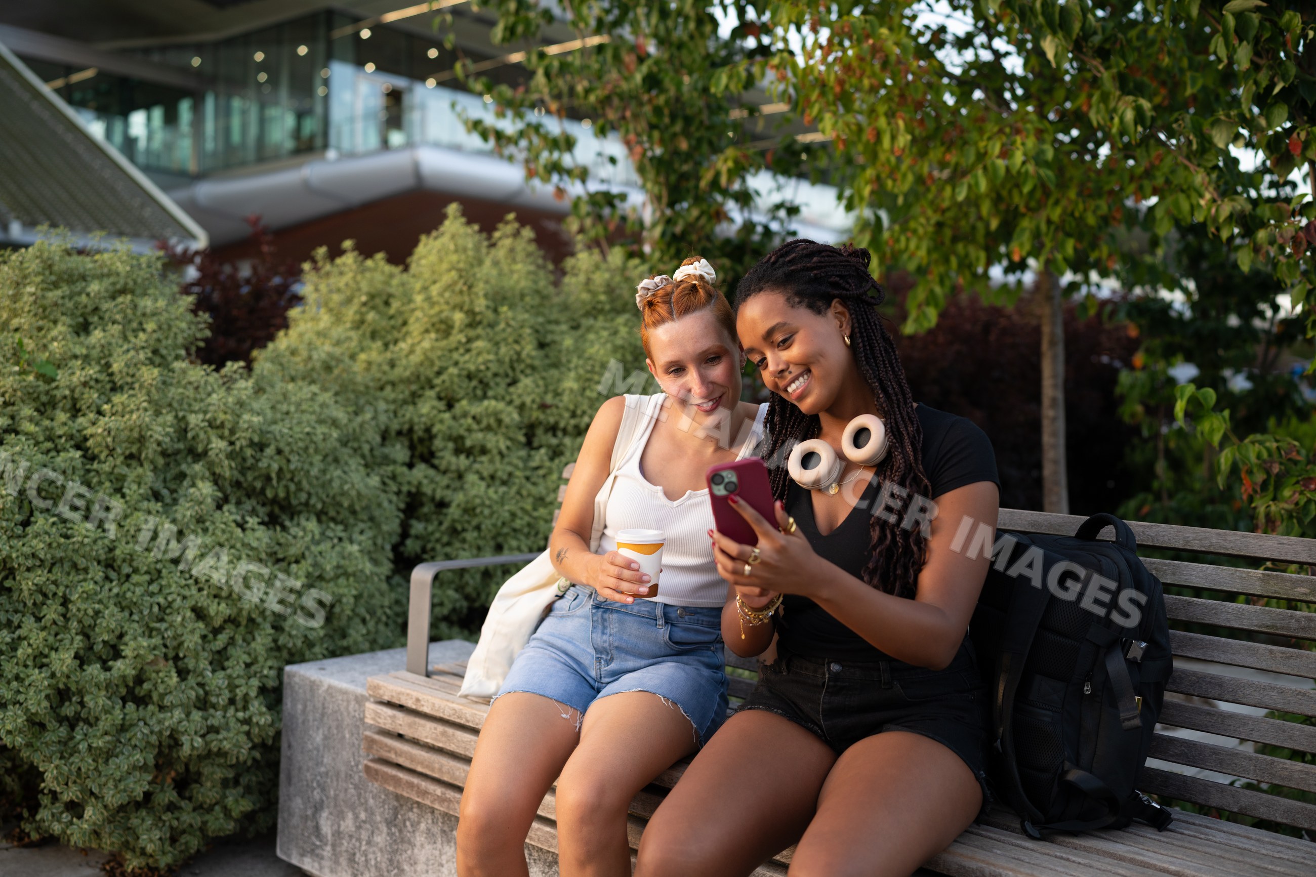 Two friends sitting on a bench looking at a smartphone in Santiago