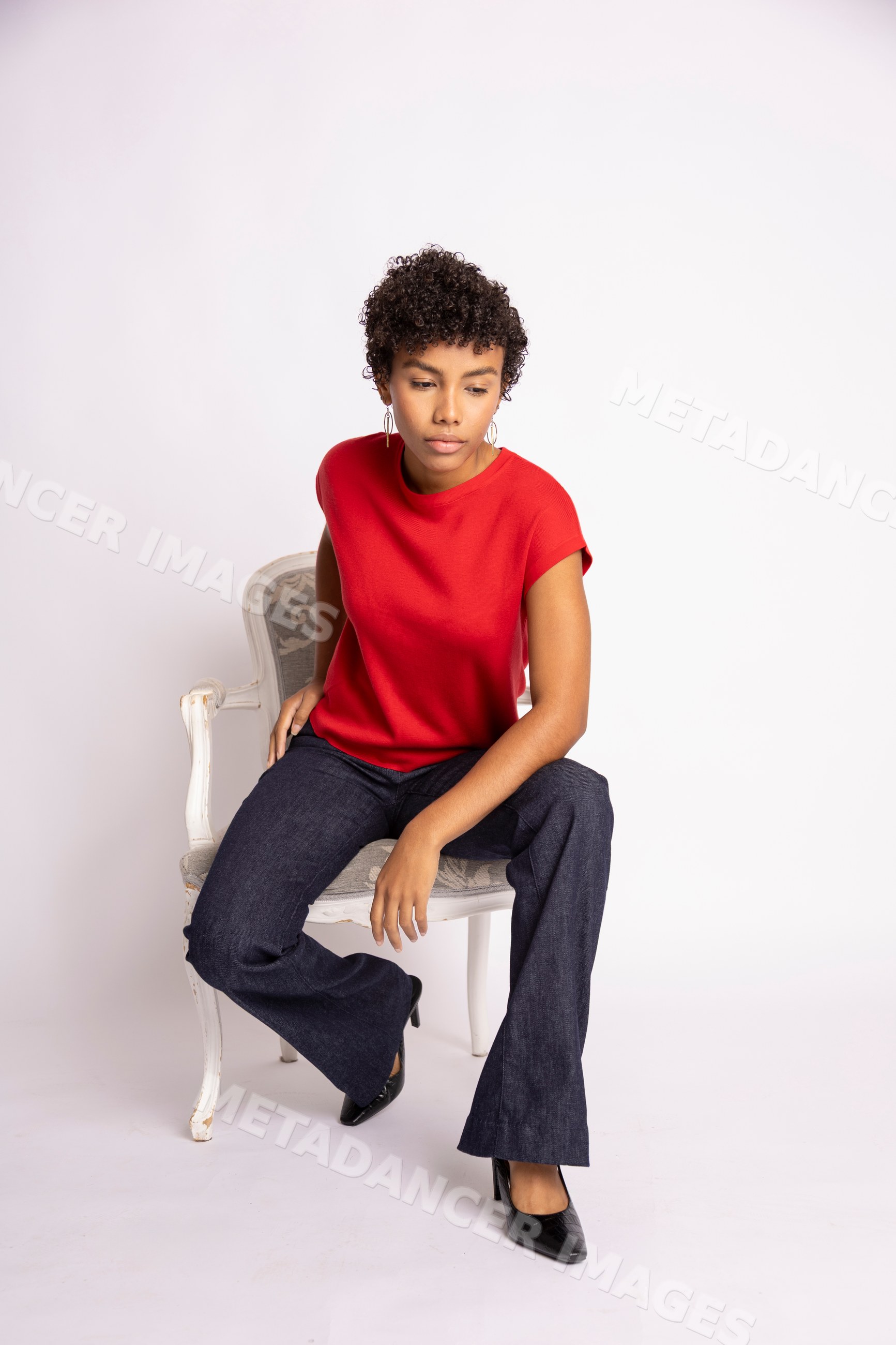 Young Hispanic woman in red short-sleeve top and jeans sitting