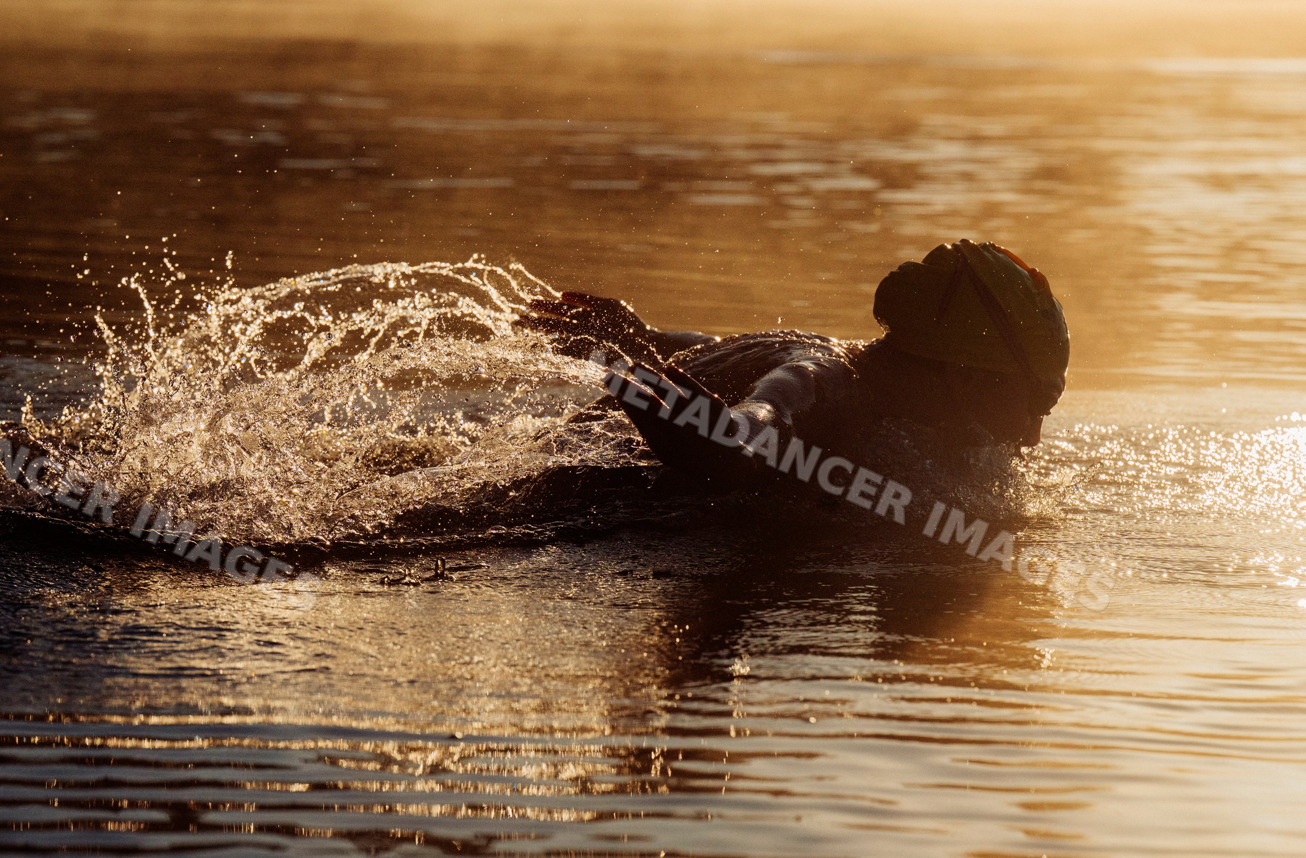 White swimmer performing backstroke in open water at sunset in the USA