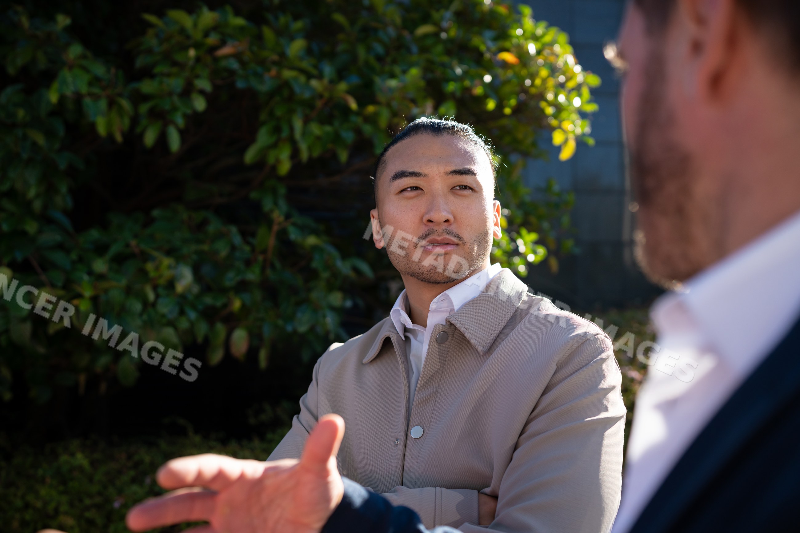 White man with bun listening during outdoor conversation