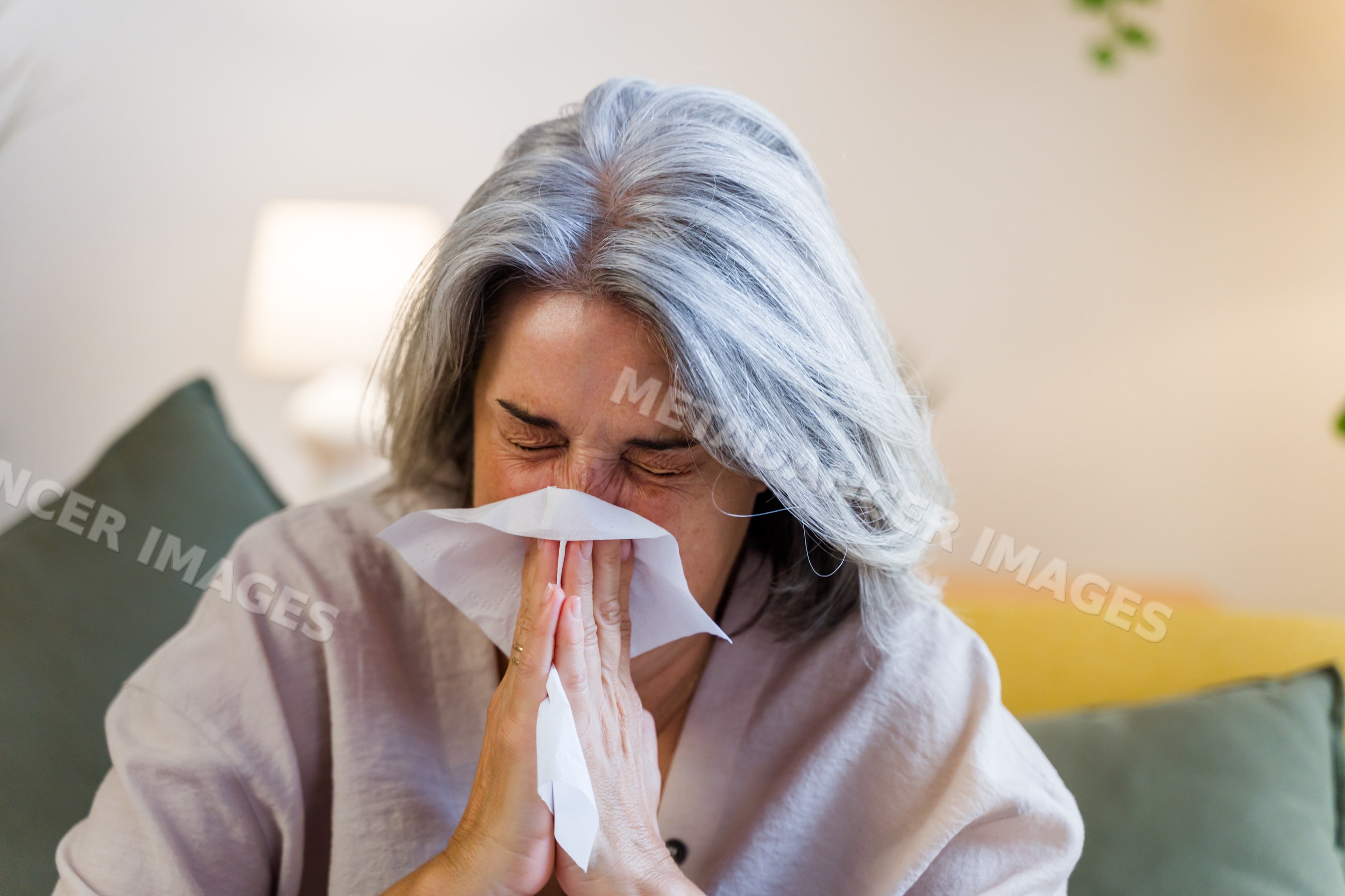 White woman sneezing into tissue